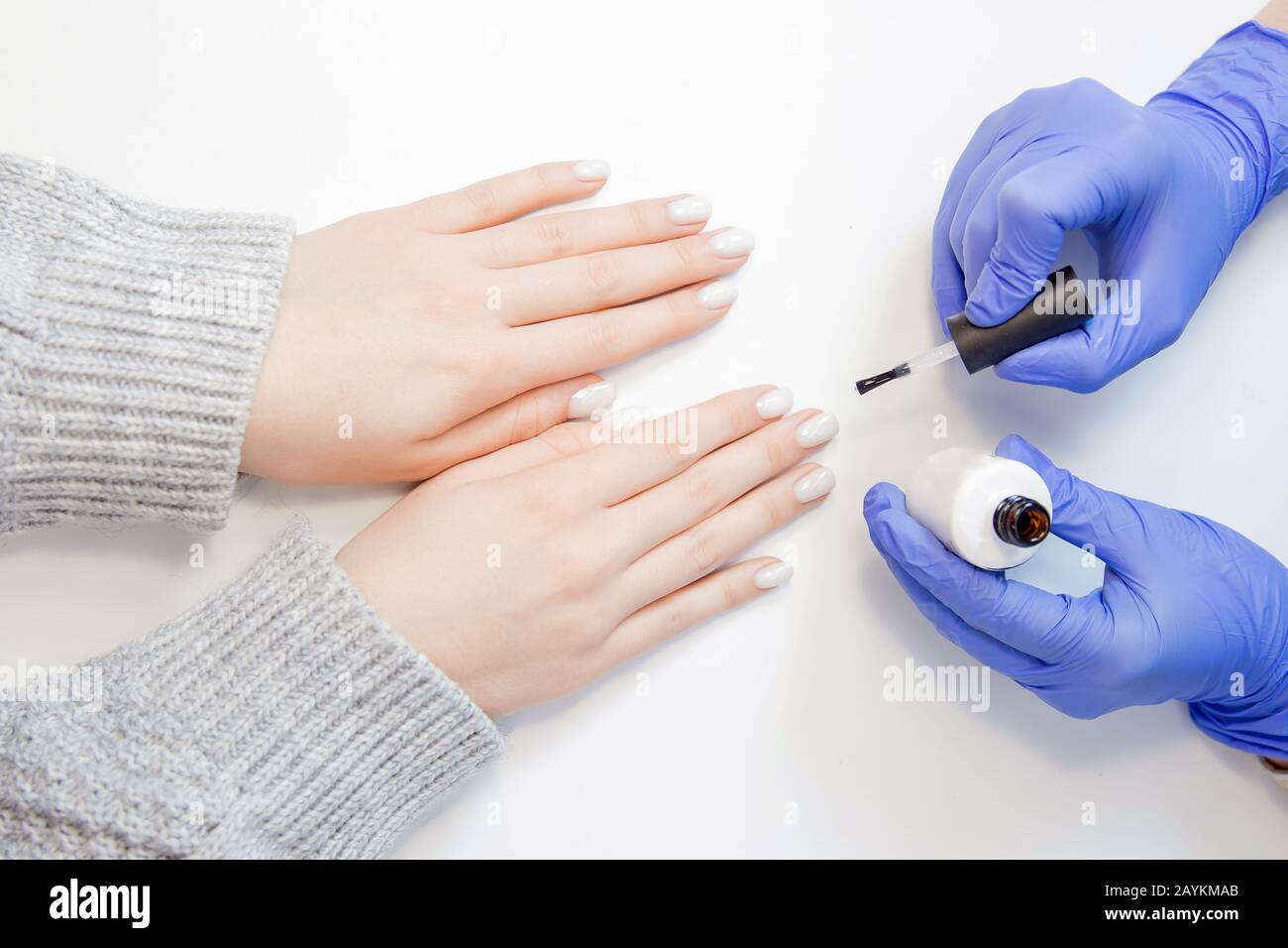 Closeup beautiful hands woman getting drawing picture nail care manicure in spa salon, white background Stock Photo