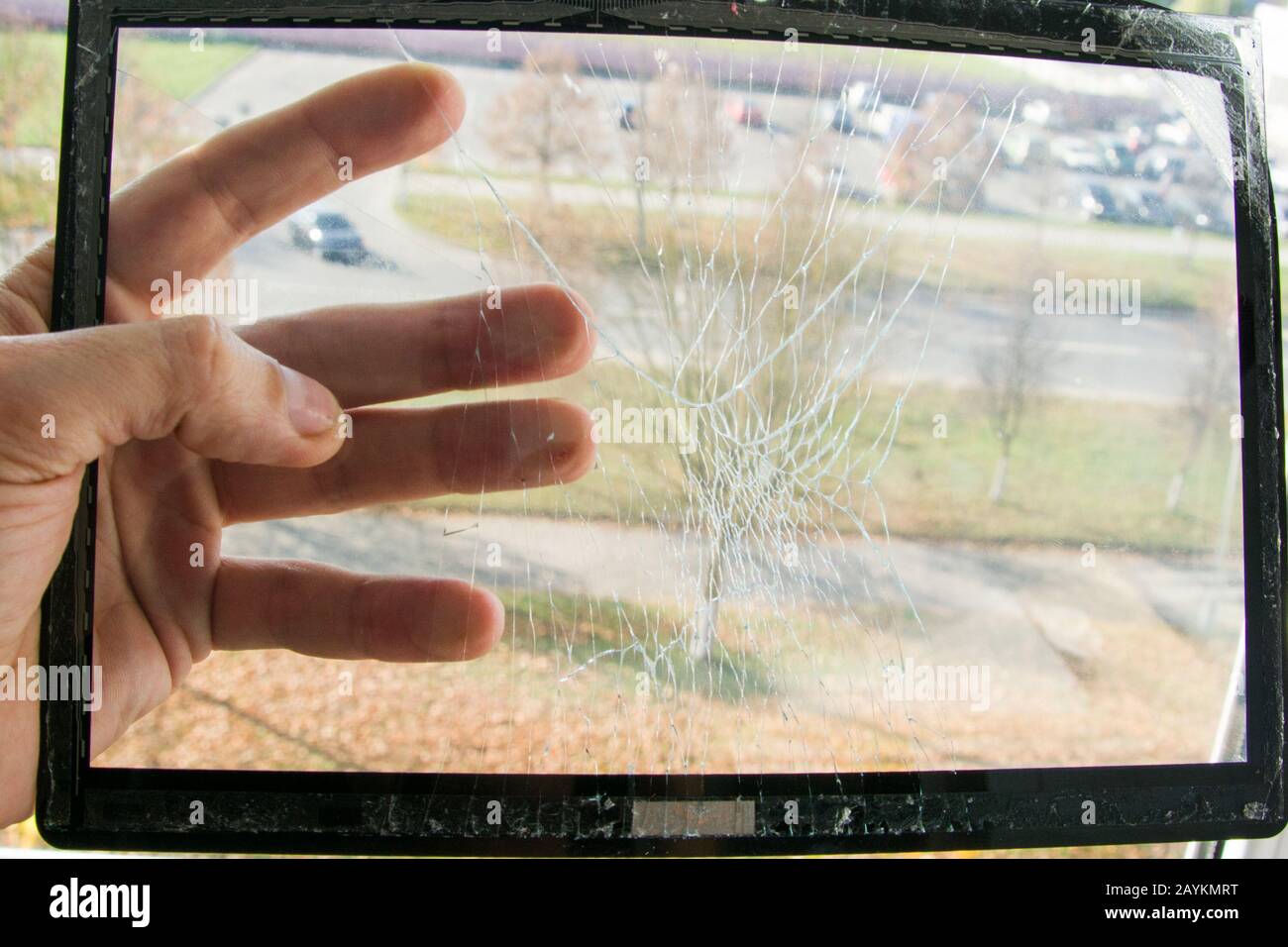 Looking through the broken touch screen damaged tablet computer. Service engineer holds a screen removed for replacement in his hand Stock Photo