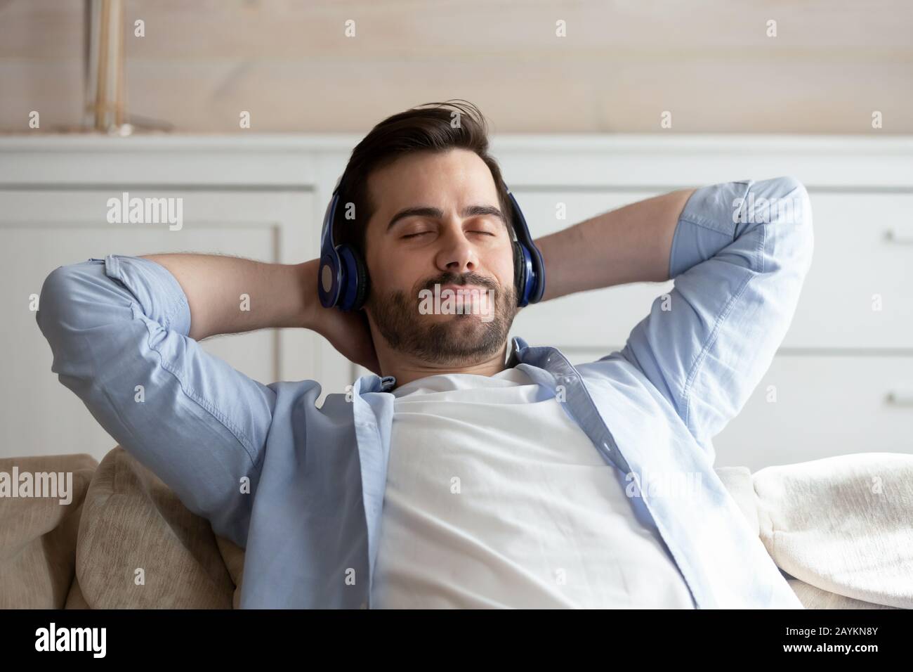 Calm young man listen to music relaxing on couch Stock Photo - Alamy