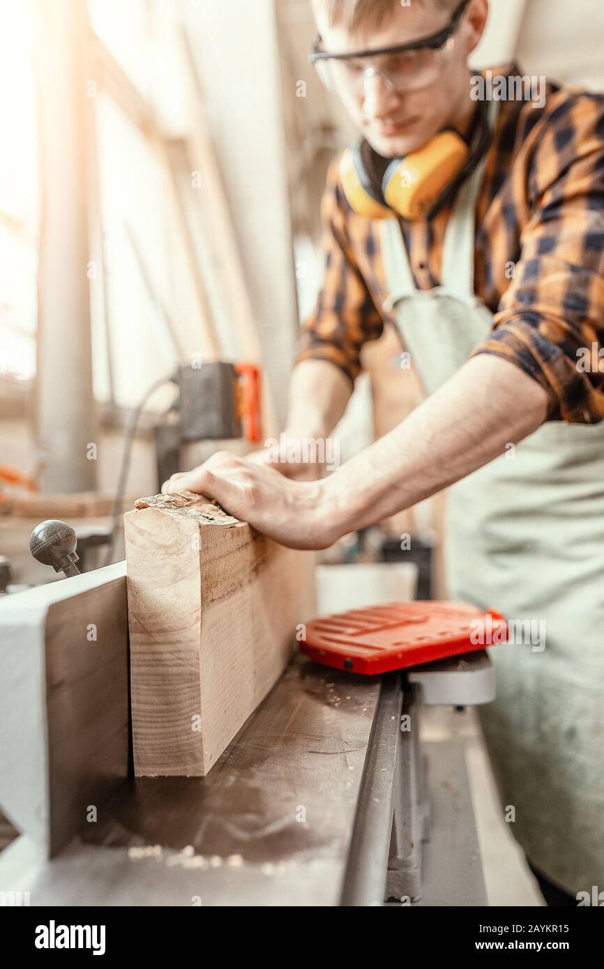 Man carpenter working with wooden workpieces at the construction site