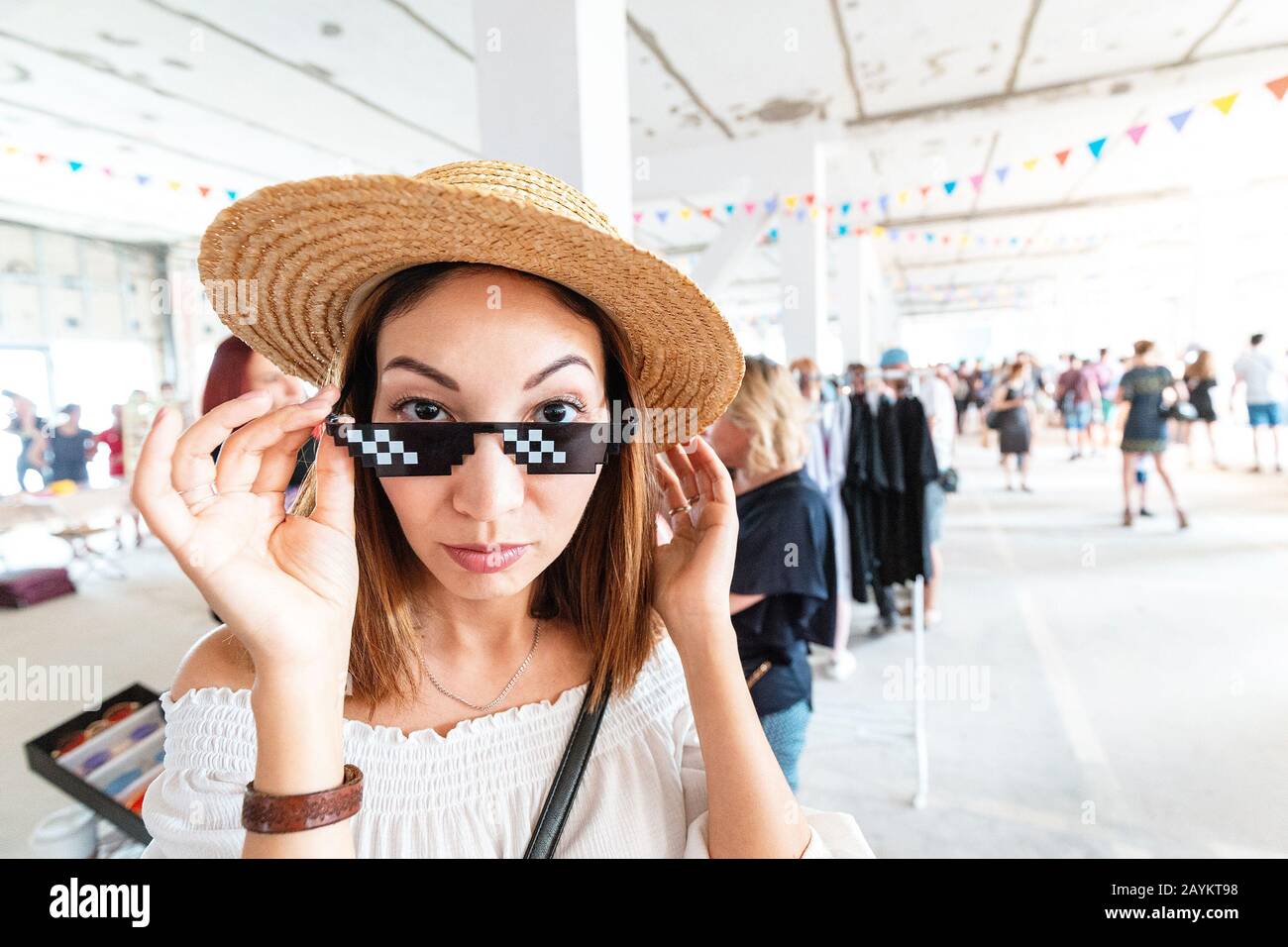 Funny girl trying on hilarious stylish sunny gangsta glasses in a store. Humor style concept Stock Photo