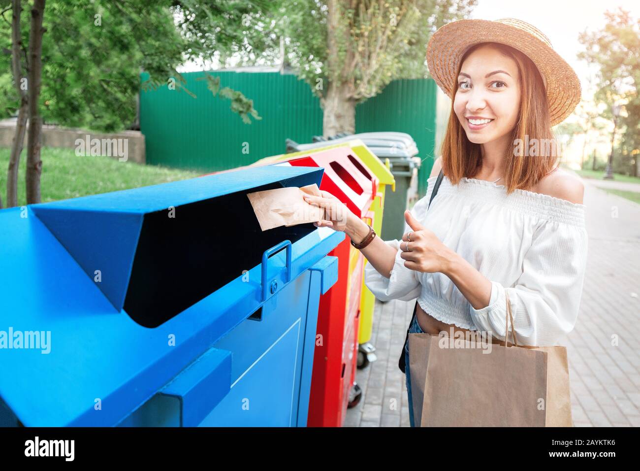 Happy asian woman throws paper in the trash garbage bin. Waste sorting concept Stock Photo