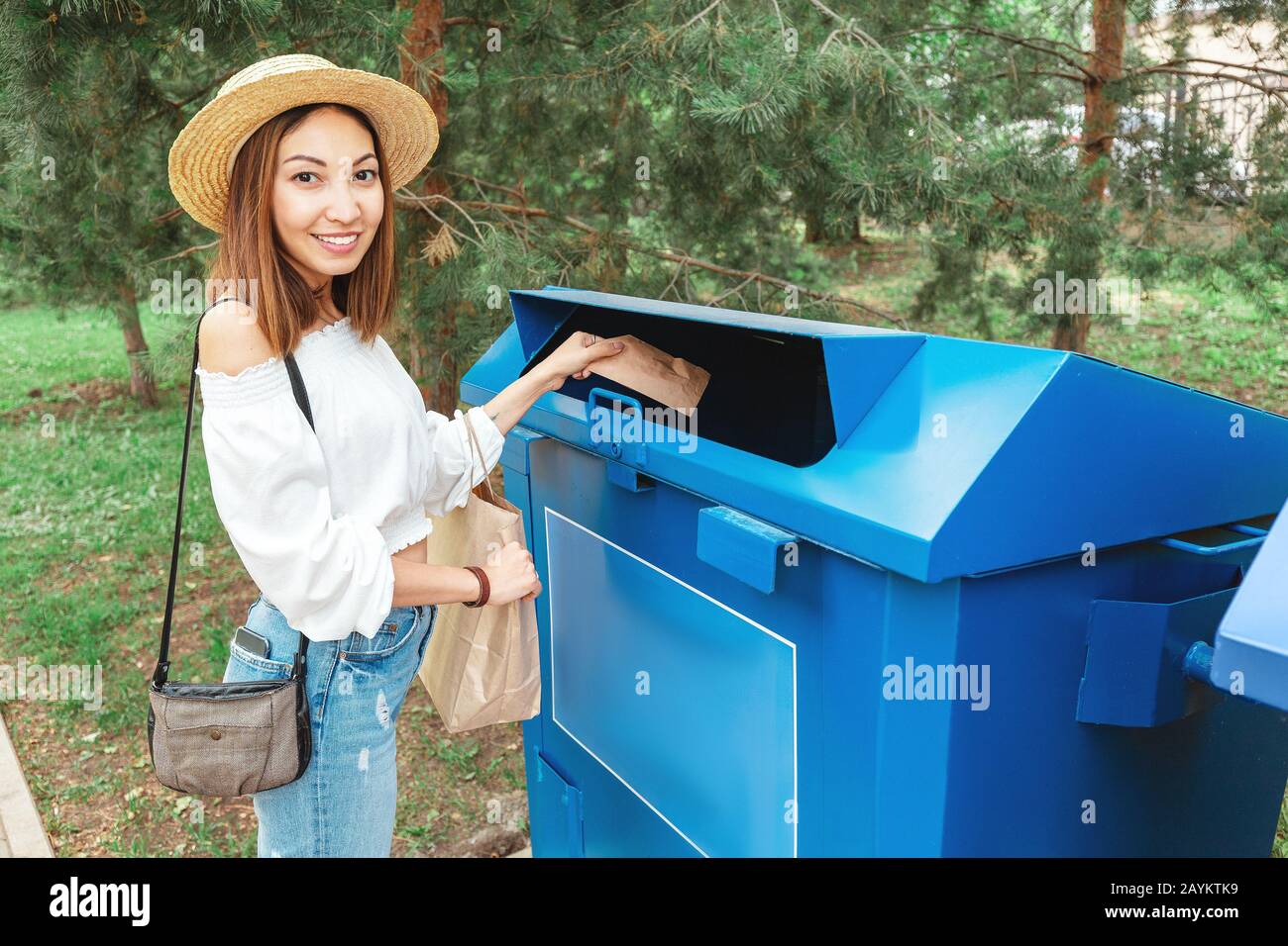 Happy asian woman throws paper in the trash garbage bin. Waste sorting concept Stock Photo
