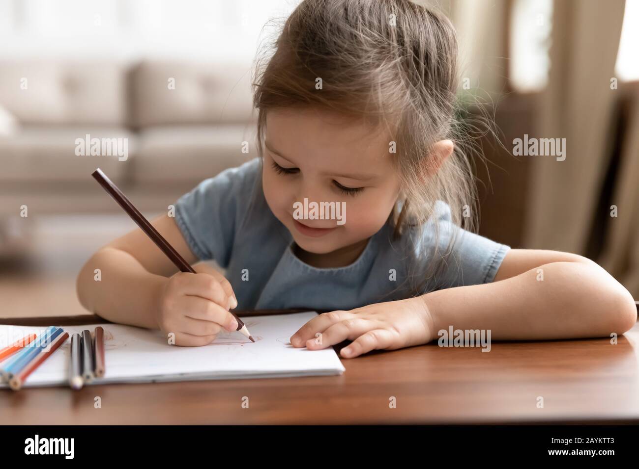 Cute little preschool child girl drawing pictures with colored pencils. Stock Photo