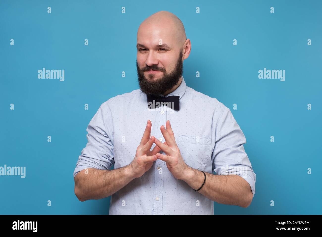 Cunning tricky mature man thinking lookingat camera with hand together over blue background. Concept of unfair game Stock Photo