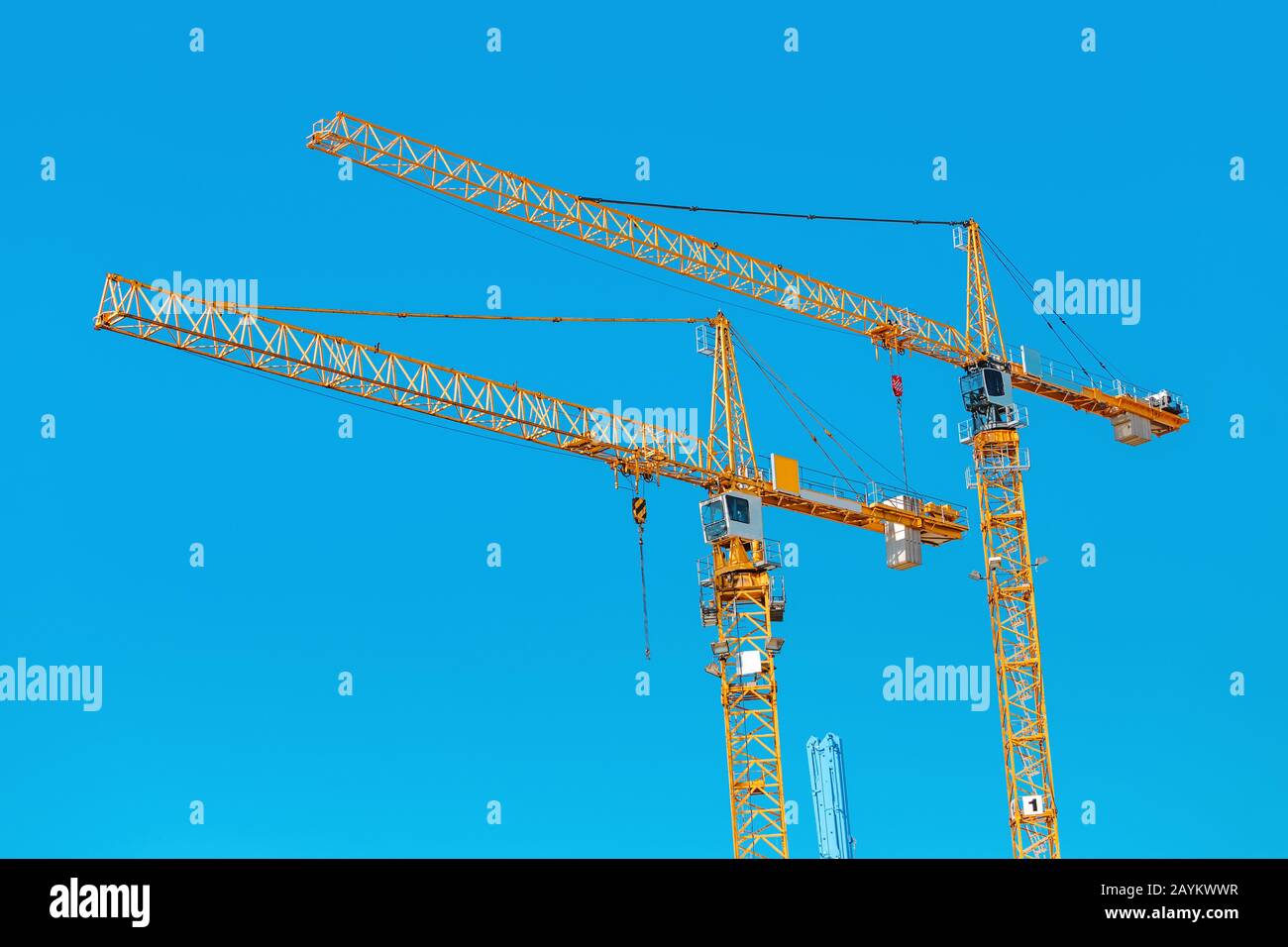 Two construction cranes against blue sky Stock Photo