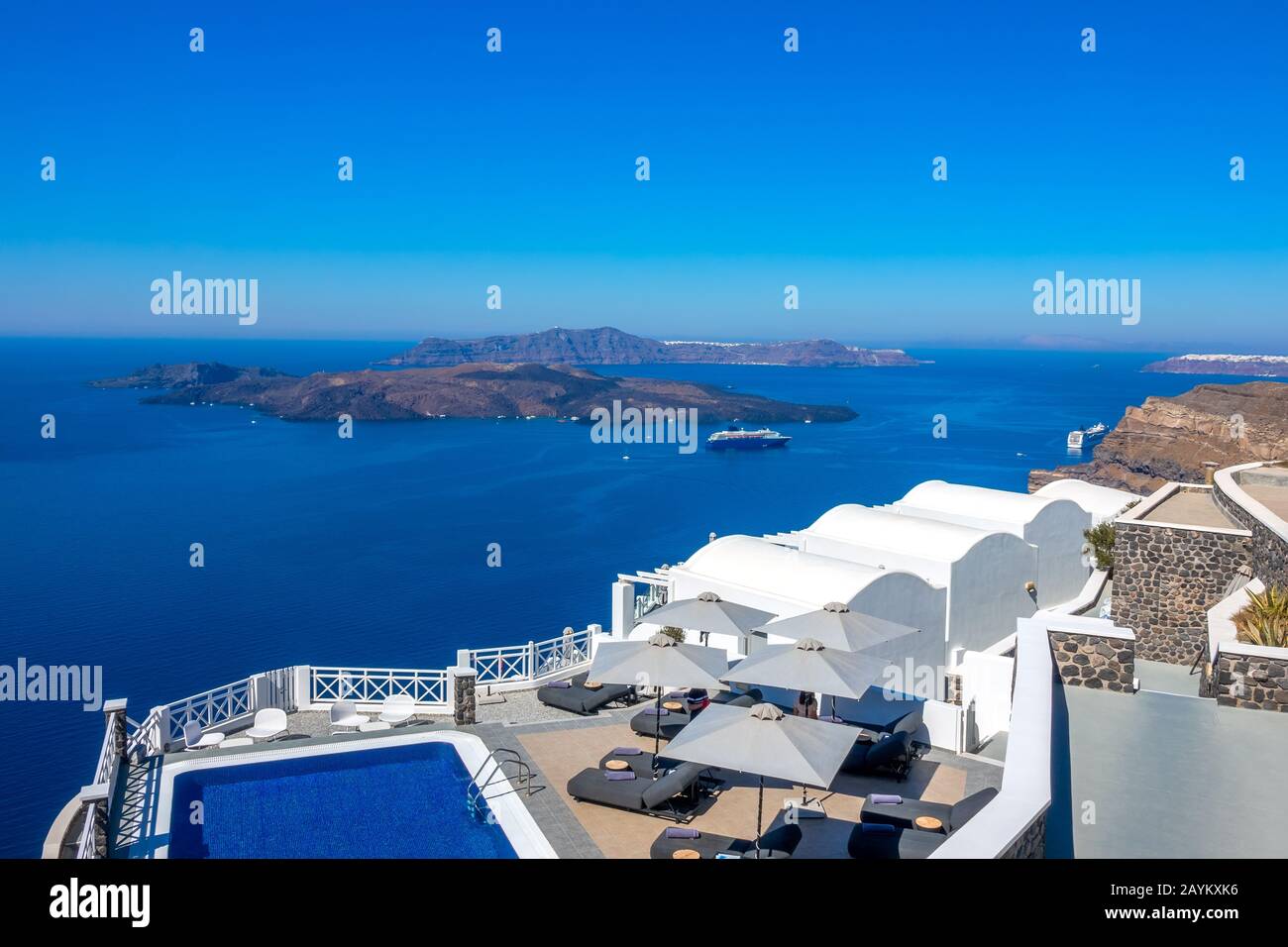 Greece. Santorini. Thira island. Hotel on the high bank in Oia. Pool and sun loungers for relaxation in sunny weather. Seascape Stock Photo