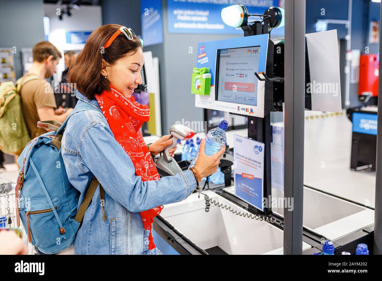 17 MAY 2018, DECATHLON, BERLIN, GERMANY: happy woman buying bottle of water  at supermarket self-service cash register Stock Photo - Alamy