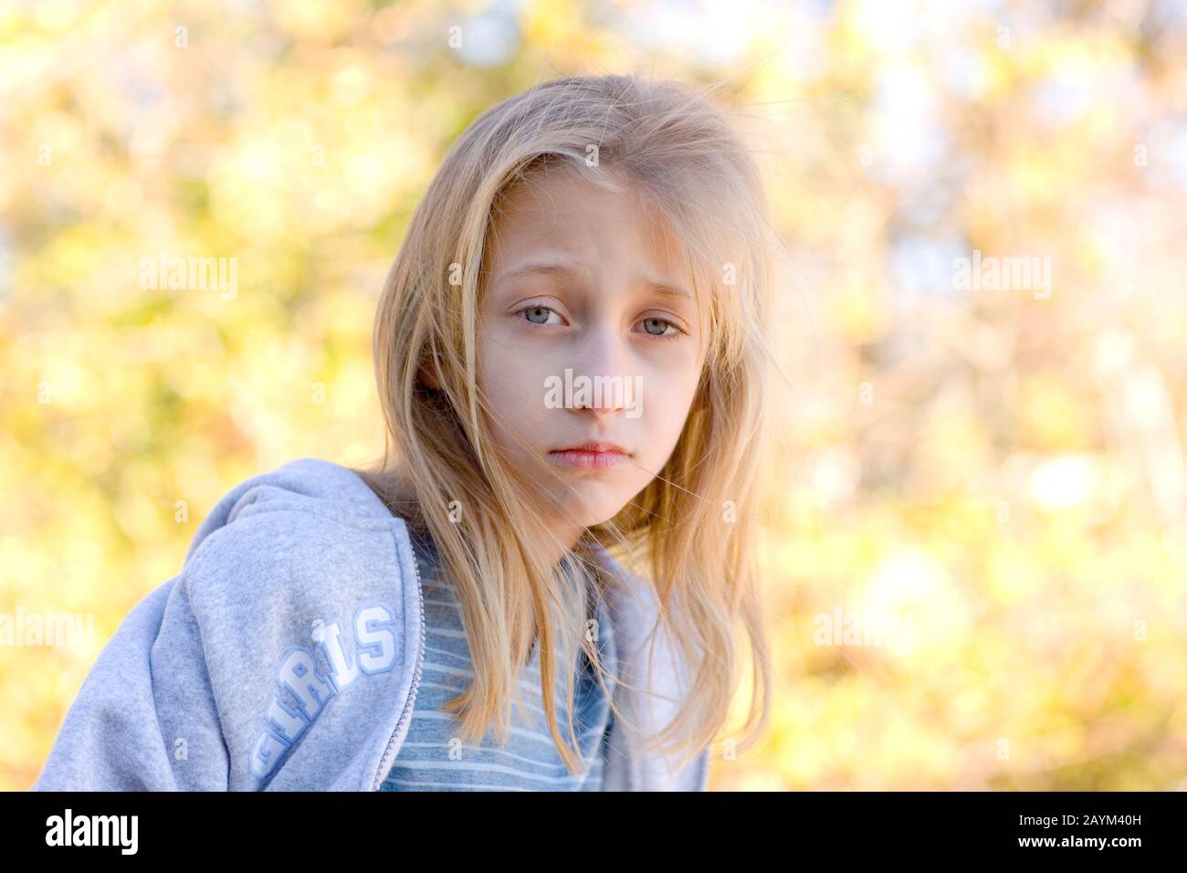 An introspective pretty young blond haired, blue eyed girl with a sad