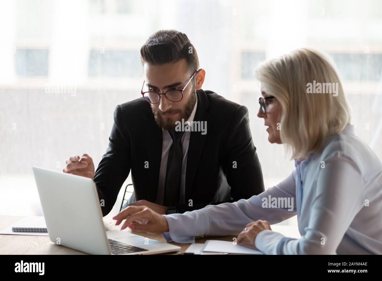 Aged mentor explain corporate app to middle eastern ethnicity employee Stock Photo