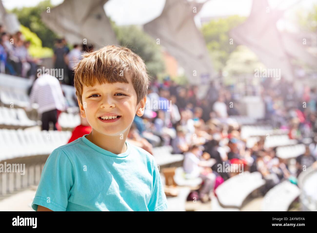 Happy smiling boy on the stadium smile and look at camera watching sport game Stock Photo
