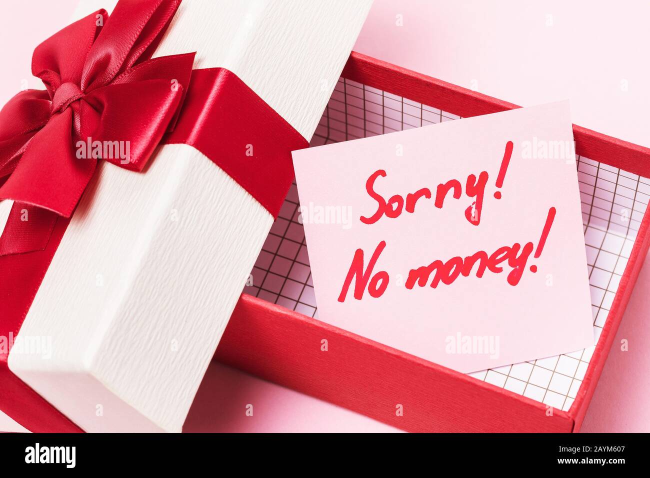 An open gift box with a note inside on a pink background. Concept on the topic of lack of money for gifts Stock Photo