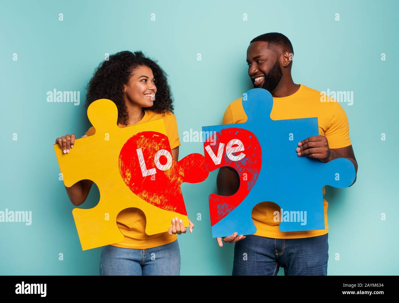 Couple with puzzles in hand over light blue background. Concept of integration, union, relationship and partnership Stock Photo
