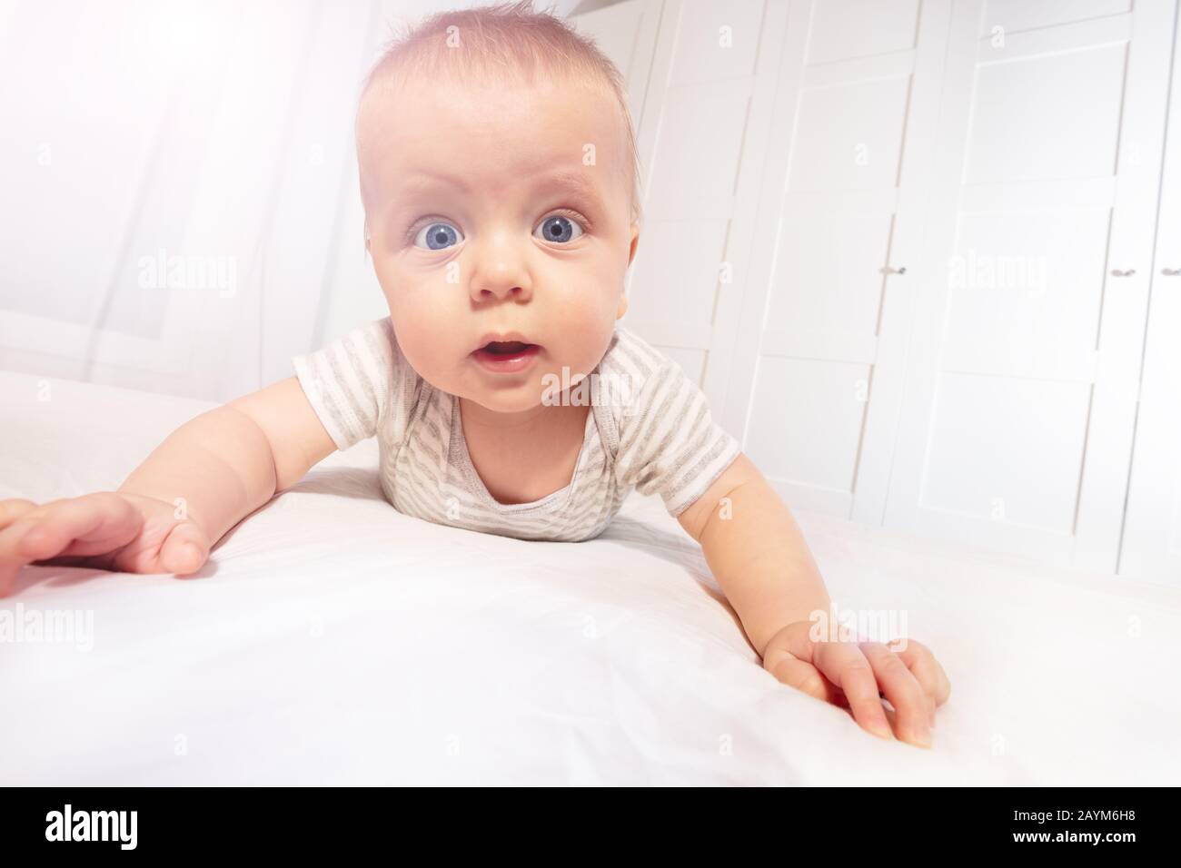 Cute little baby boy toddler learn to crawl view from low angle looking at camera Stock Photo