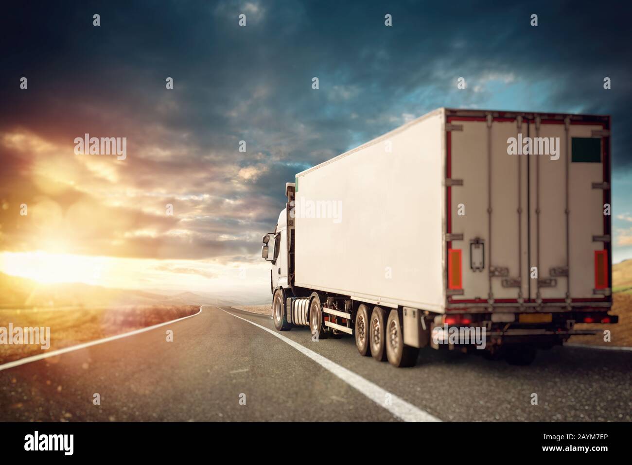 White truck moving on the road in a natural landscape at sunset. Stock Photo