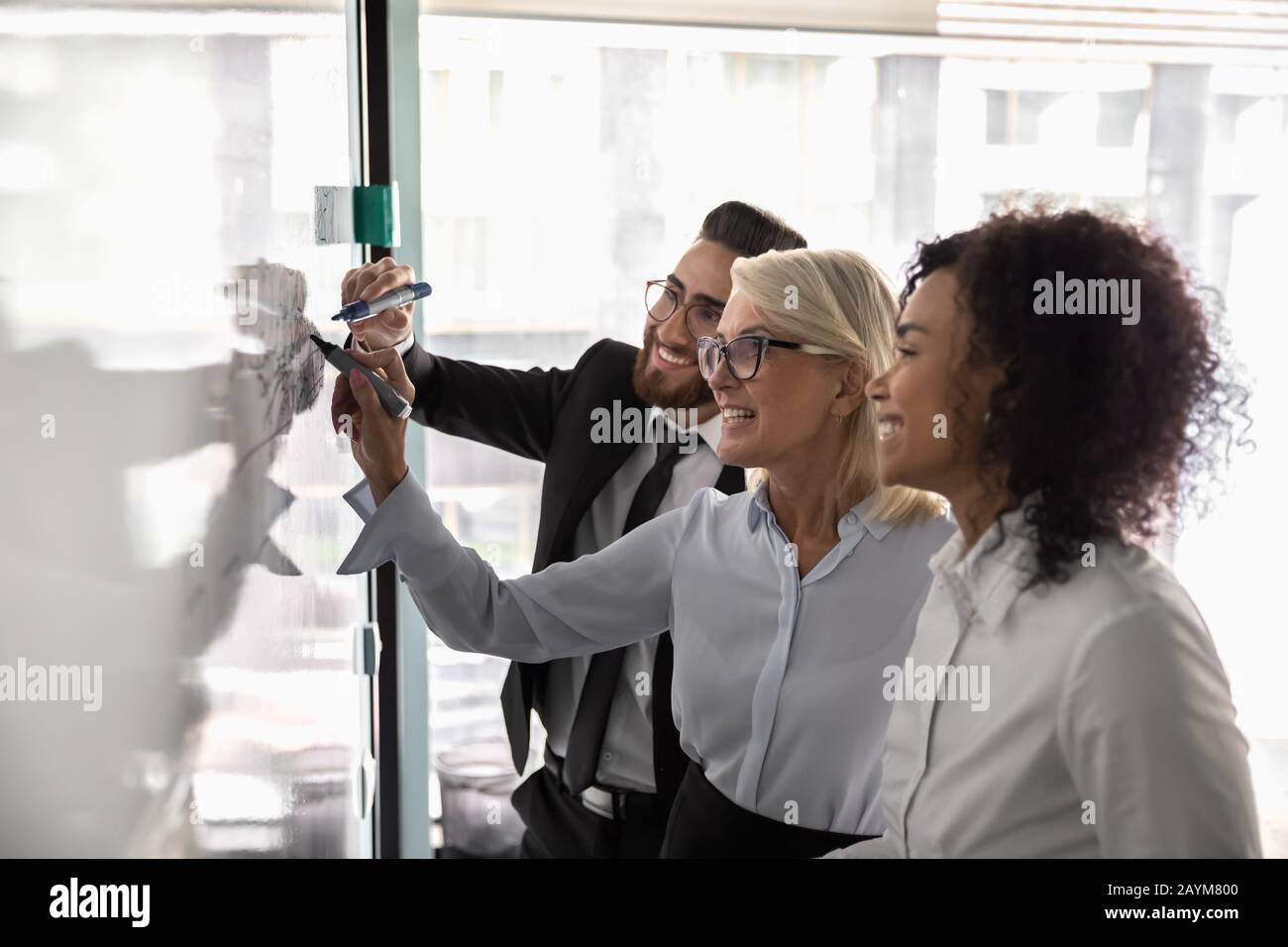 Three diverse entrepreneurs working on business strategy using white board Stock Photo