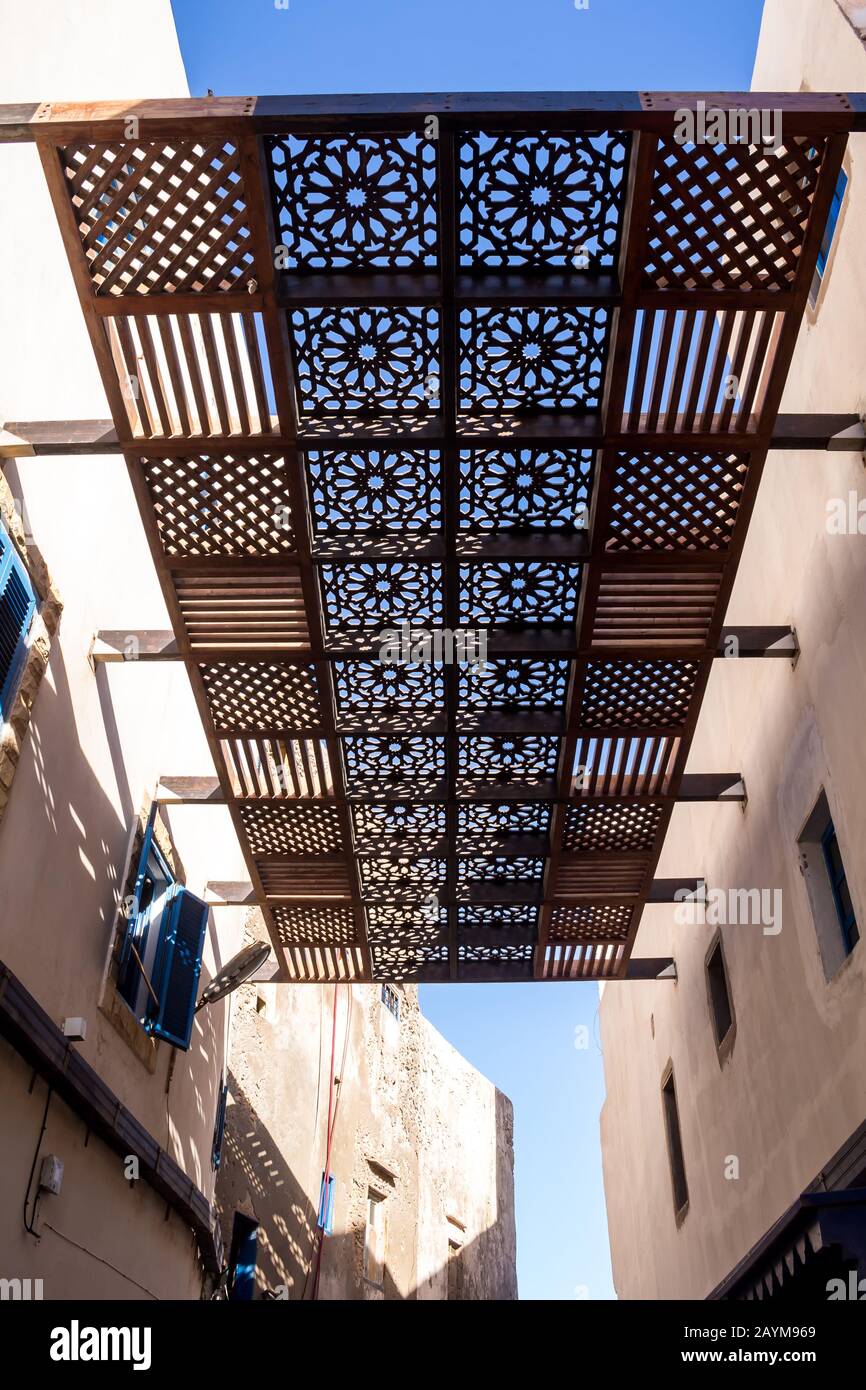 White weathered facade of the houses with small windows. Wooden sun shade  above the street. Bright blue sky. Essaouira, Morocco Stock Photo - Alamy
