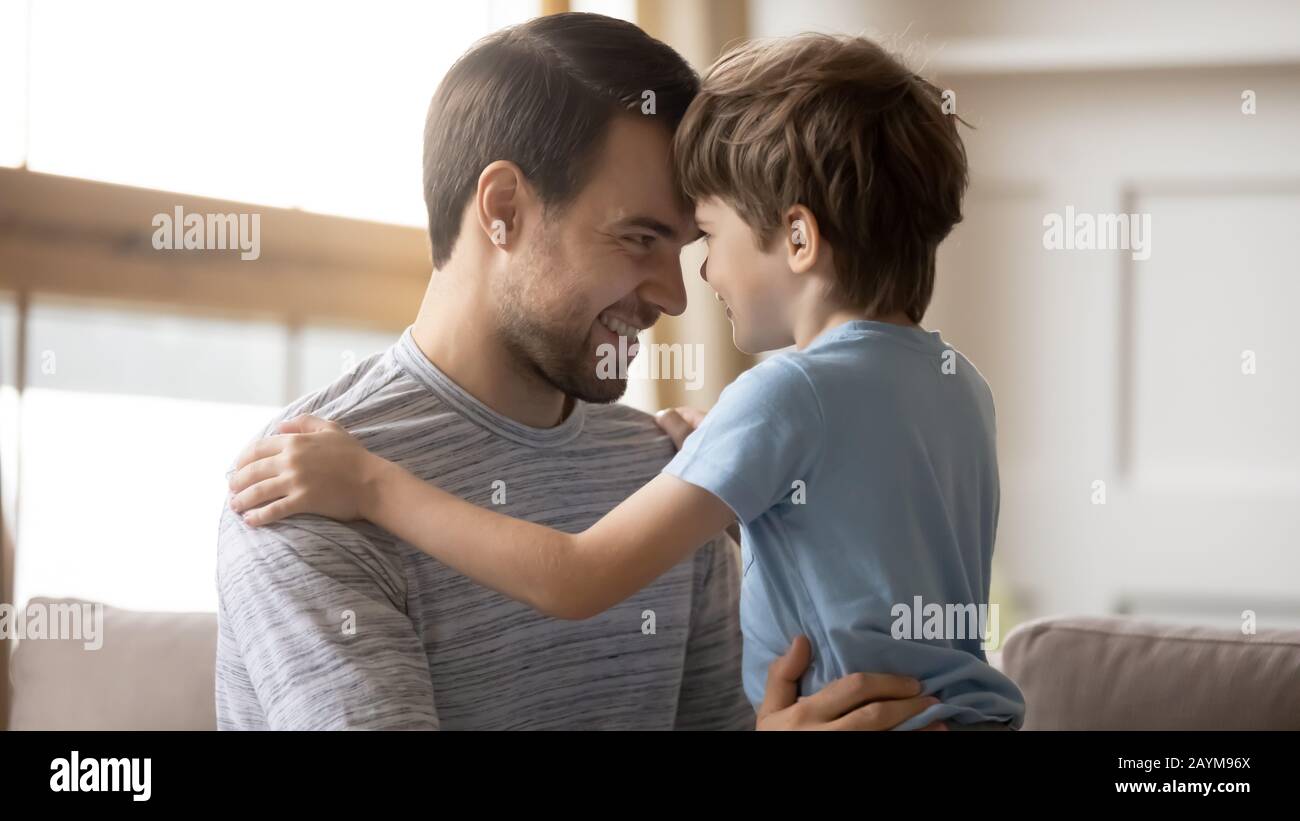 Affectionate young smiling father touching foreheads with little child. Stock Photo