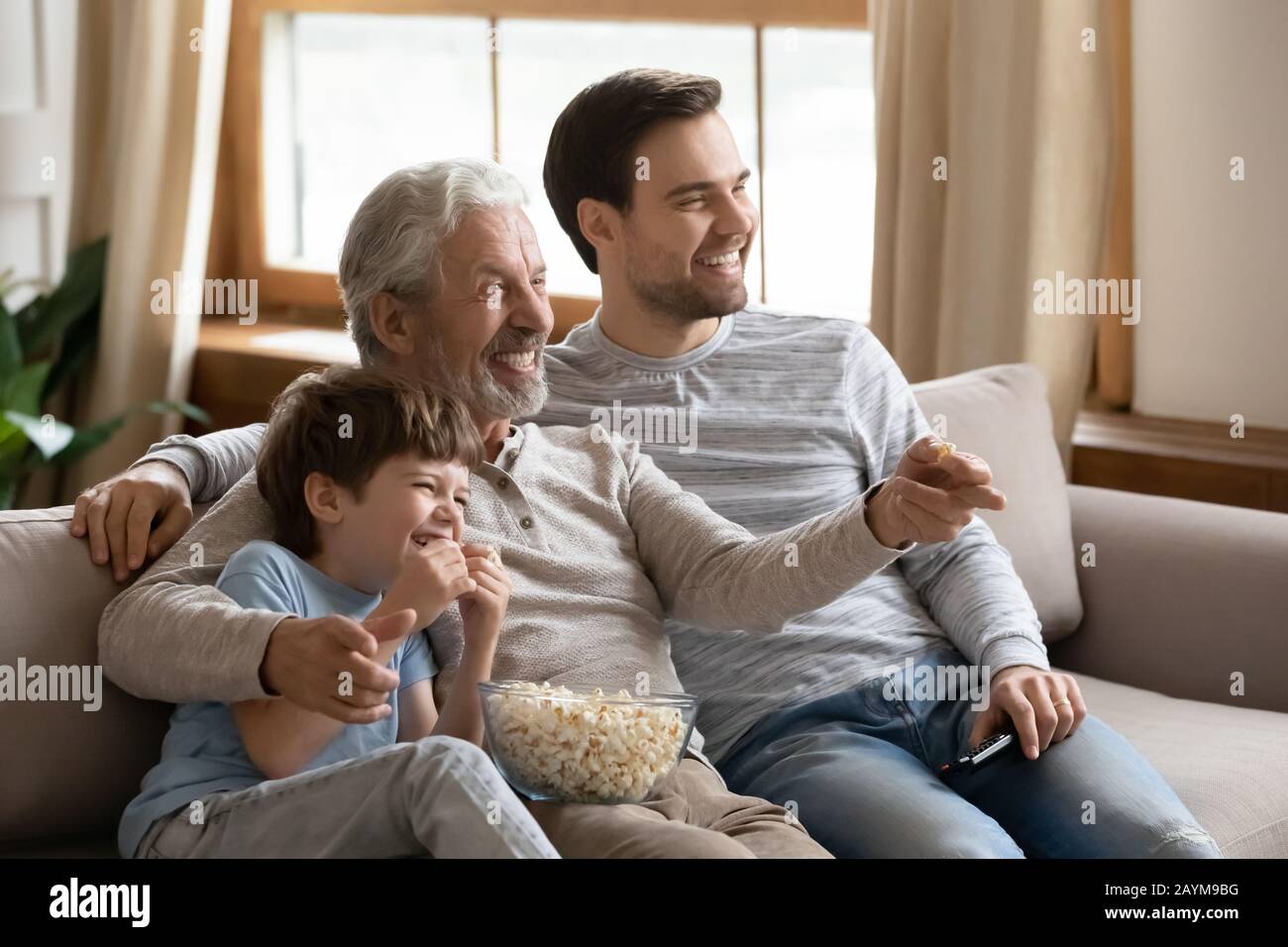 Happy three generations male family watching football championship match. Stock Photo