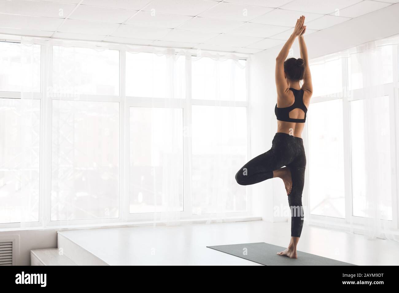 Woman exercising yoga in tree pose at home Stock Photo - Alamy