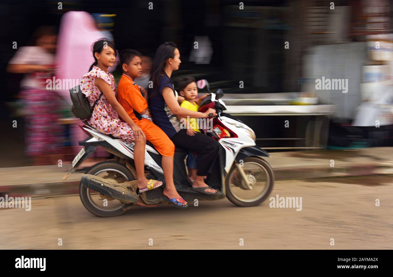 four people on the same motor bike in the old town, Thailand, Phuket Stock Photo