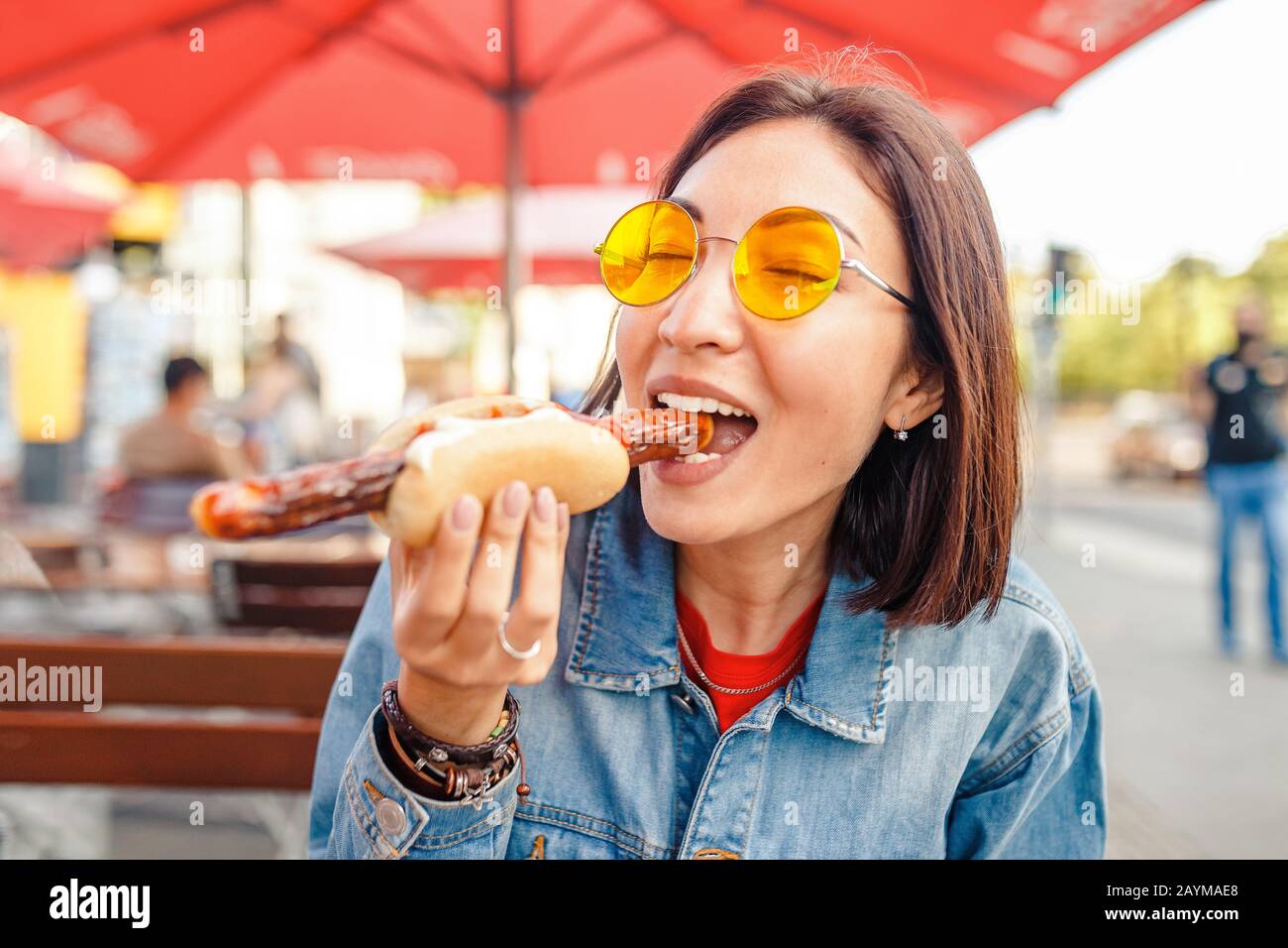 Woman eating Currywurst fast food German sausage in outdoor street food cafe Stock Photo