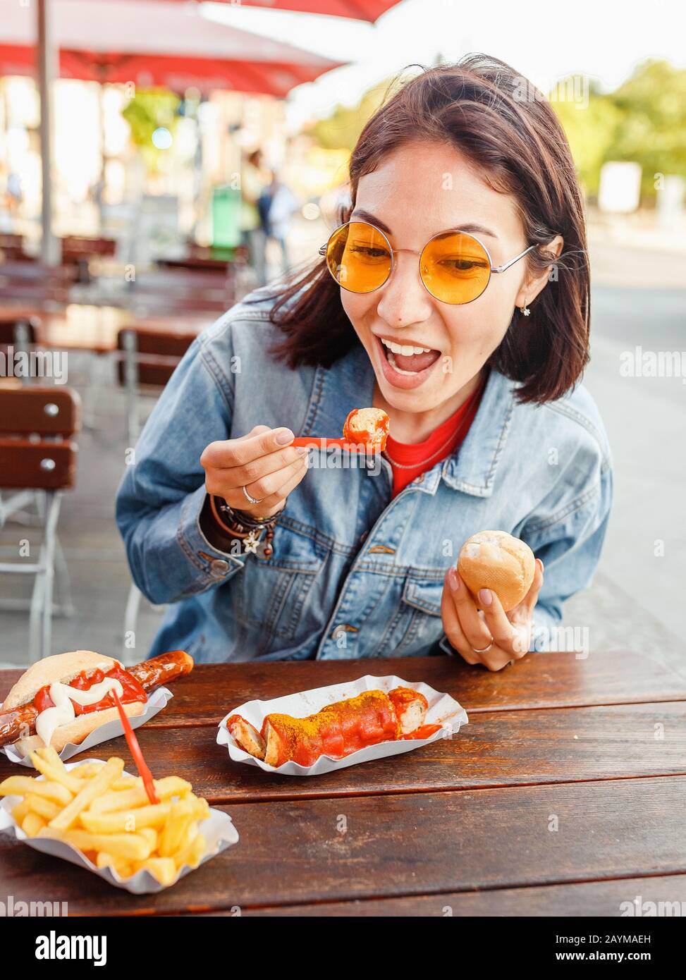 Woman eating Currywurst fast food German sausage in outdoor street food cafe Stock Photo