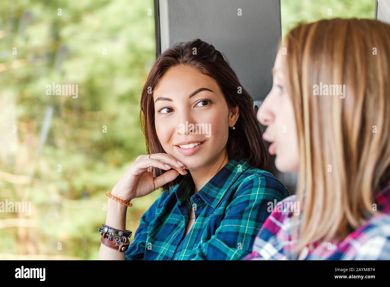 Two women Friends talk and laugh while traveling by train or bus Stock Photo