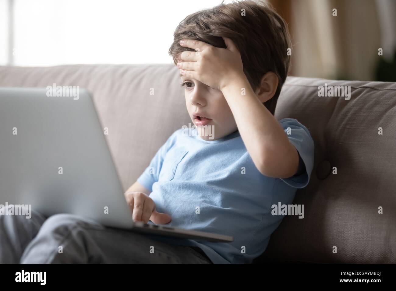 Little boy hocked by inappropriate content, looking at computer screen. Stock Photo