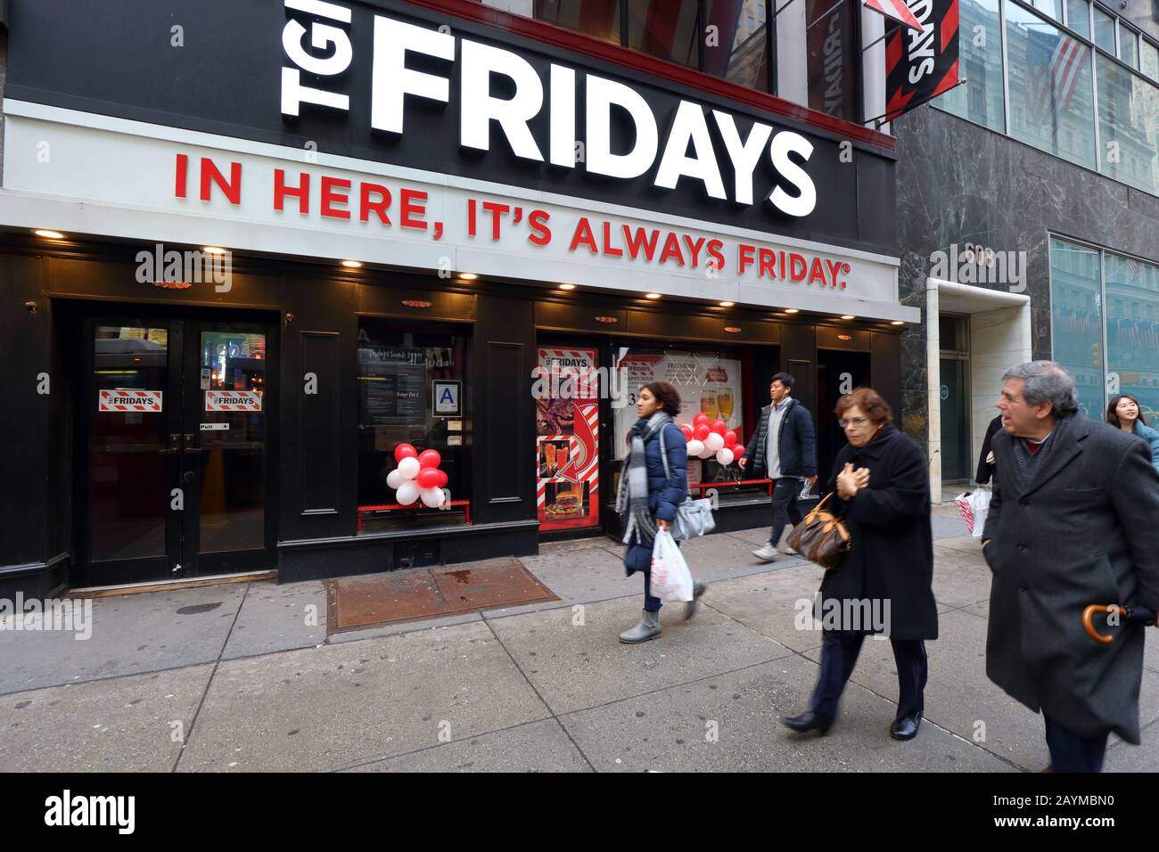 People walking past a TGI Fridays happy hour themed chain restaurant at 604 5th Ave in Midtown Manhattan, New York, NY. Stock Photo