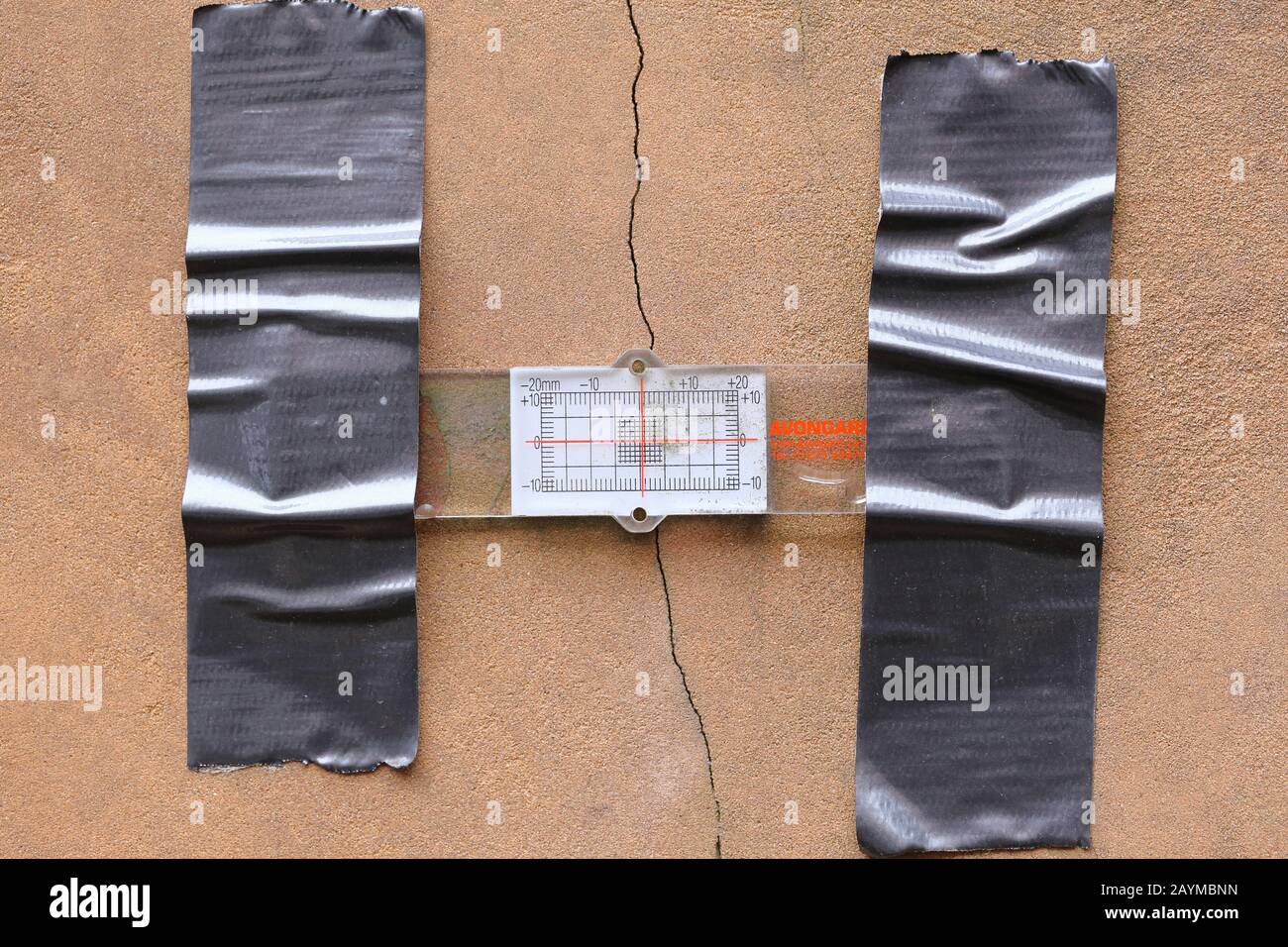 A crack gauge monitors the size of a crack in a sandstone wall Stock Photo