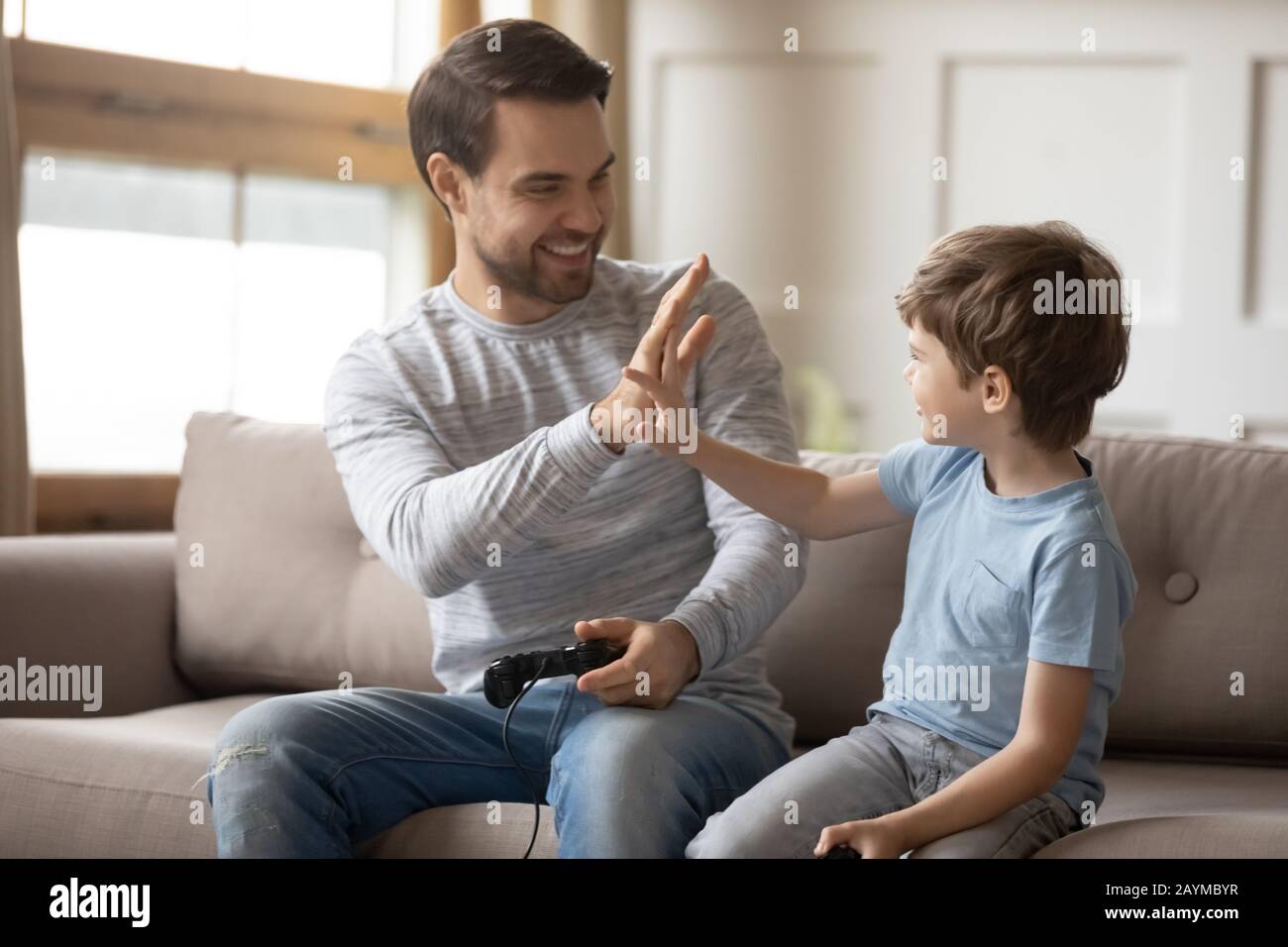 Excited young father giving high five to happy little son. Stock Photo