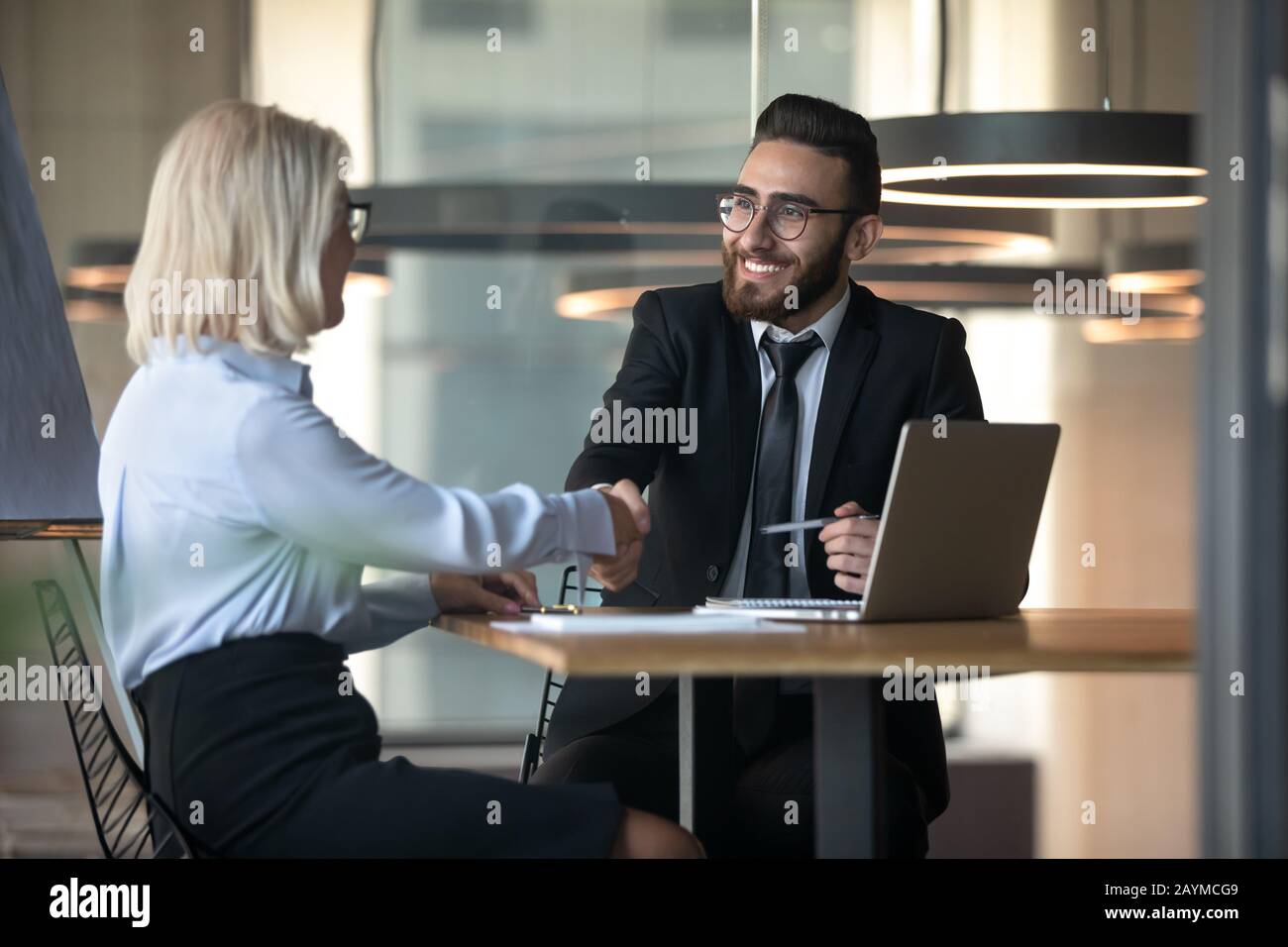 Middle eastern ethnicity HR manager hiring elderly woman people handshaking Stock Photo