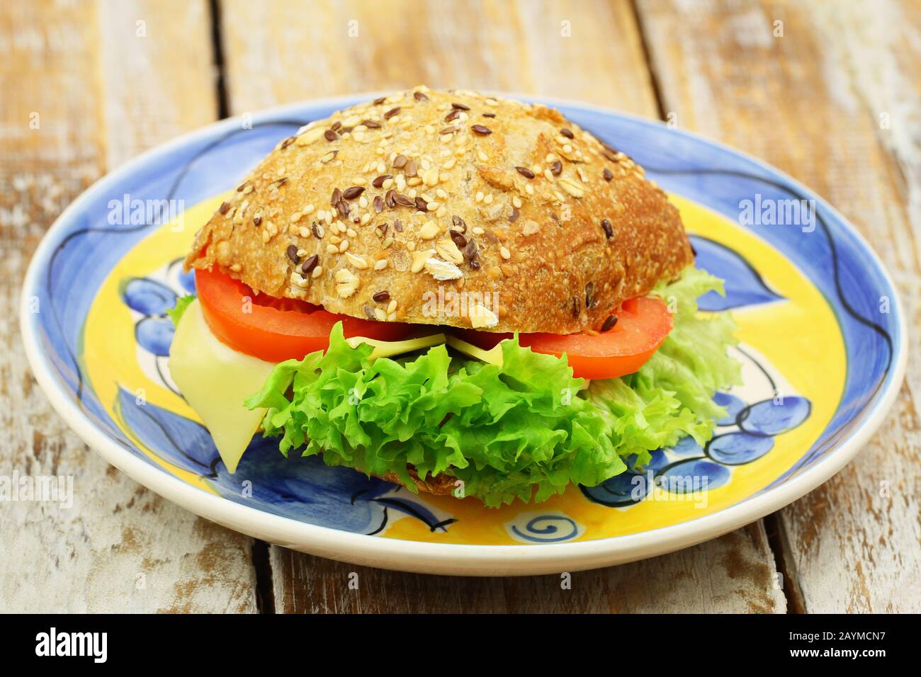 Mixed grain roll with cheese, lettuce and tomato on vintage plate, closeup Stock Photo