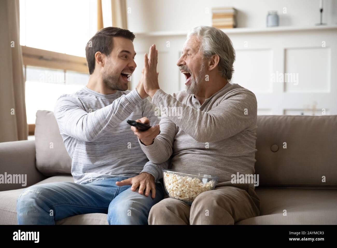 Happy young man giving high five to overjoyed father. Stock Photo