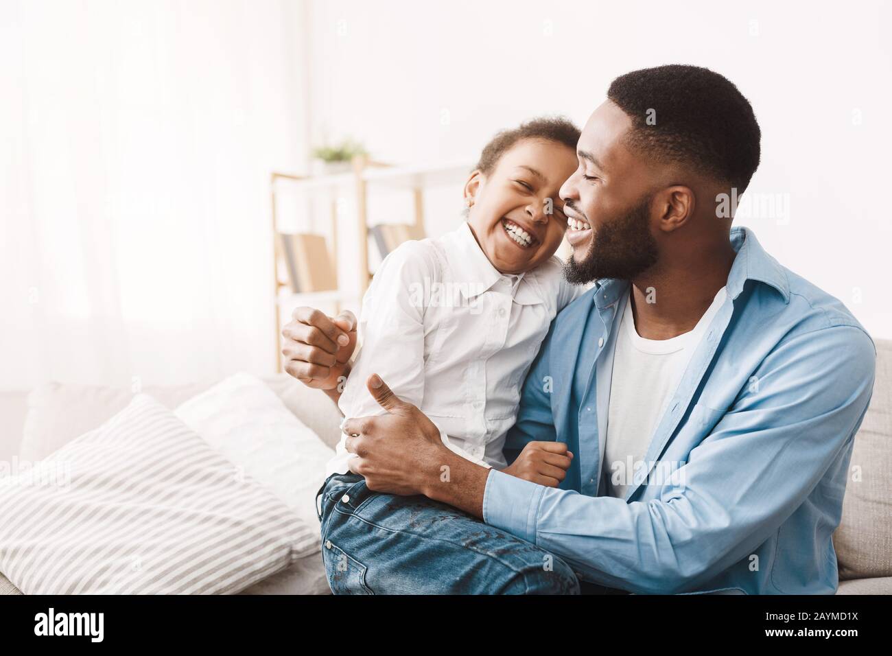 Genuine emotions. African dad tickling cute daughter Stock Photo