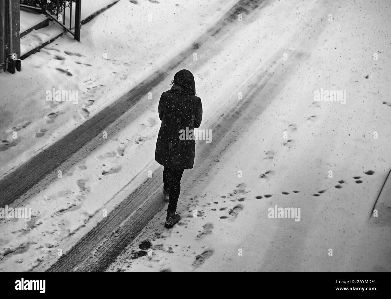 Woman walking in snow on urban street, winter season Stock Photo