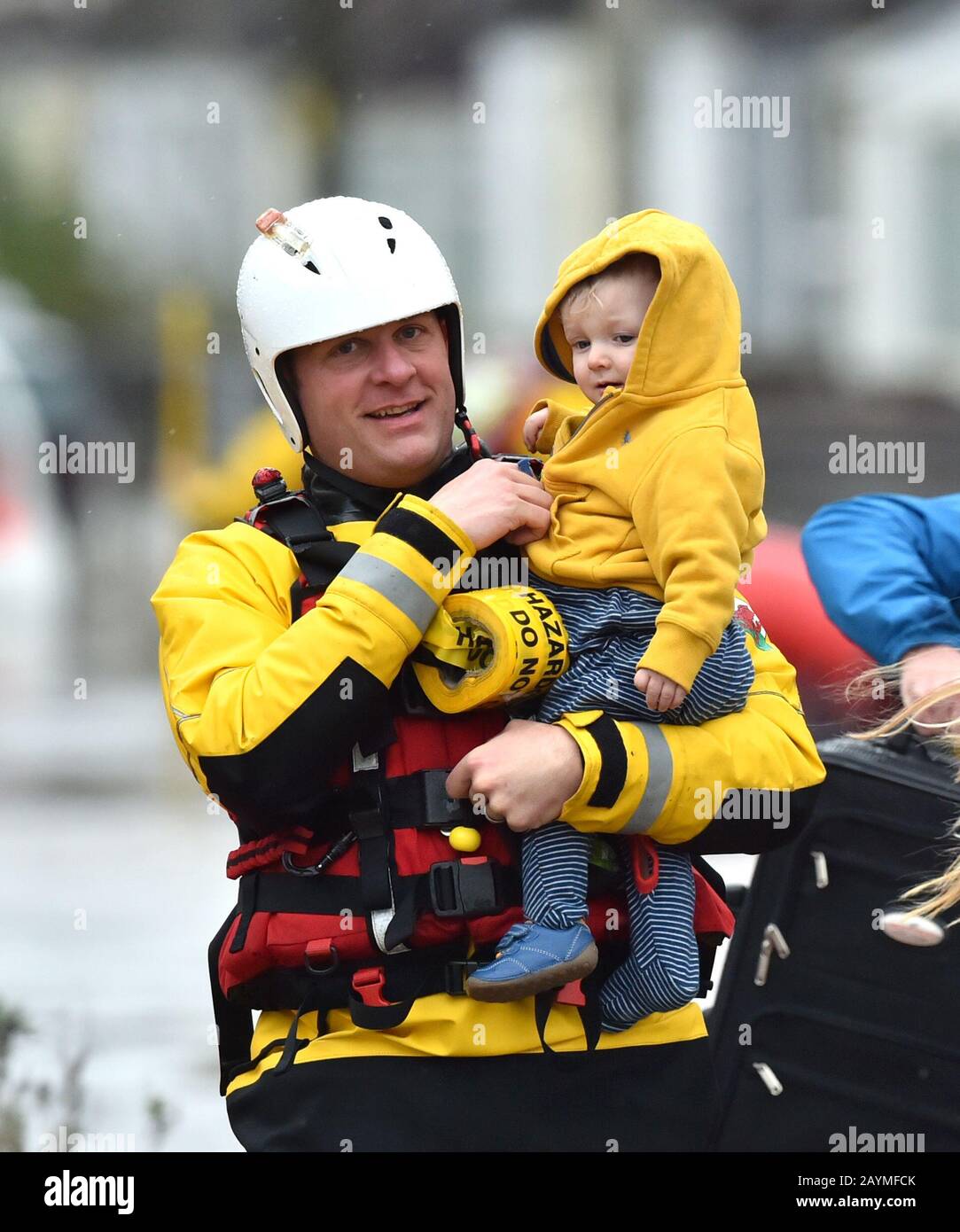 One-year-old Blake is carried by a rescue worker as emergency services continue to take families to safety, after flooding in Nantgarw, Wales, as Storm Dennis hit the UK. Stock Photo