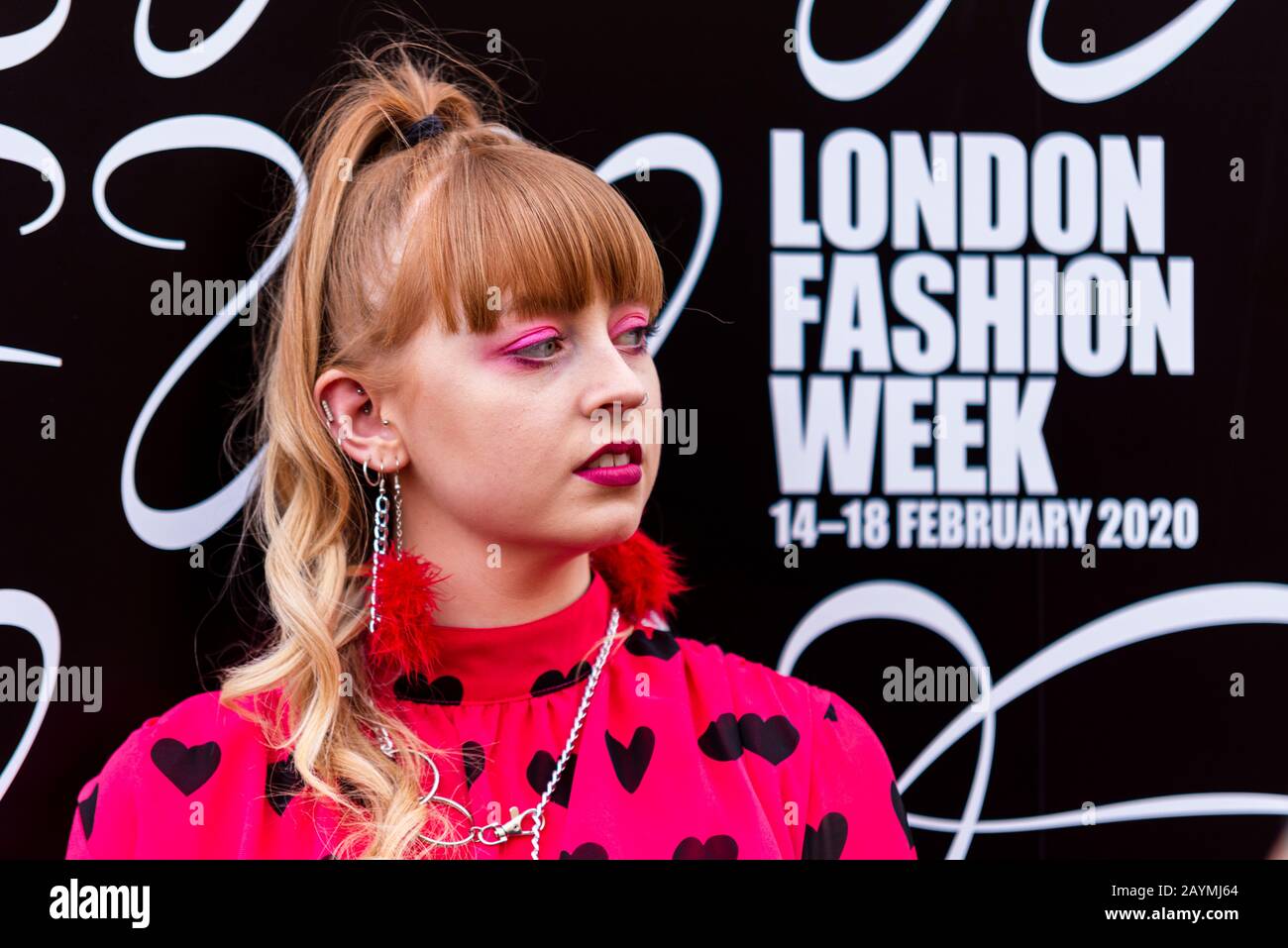 A fashionista female posing in the Strand outside The Store during London Fashion Week 2020. Brand. Logo. Pink eye shadow. Dates Stock Photo
