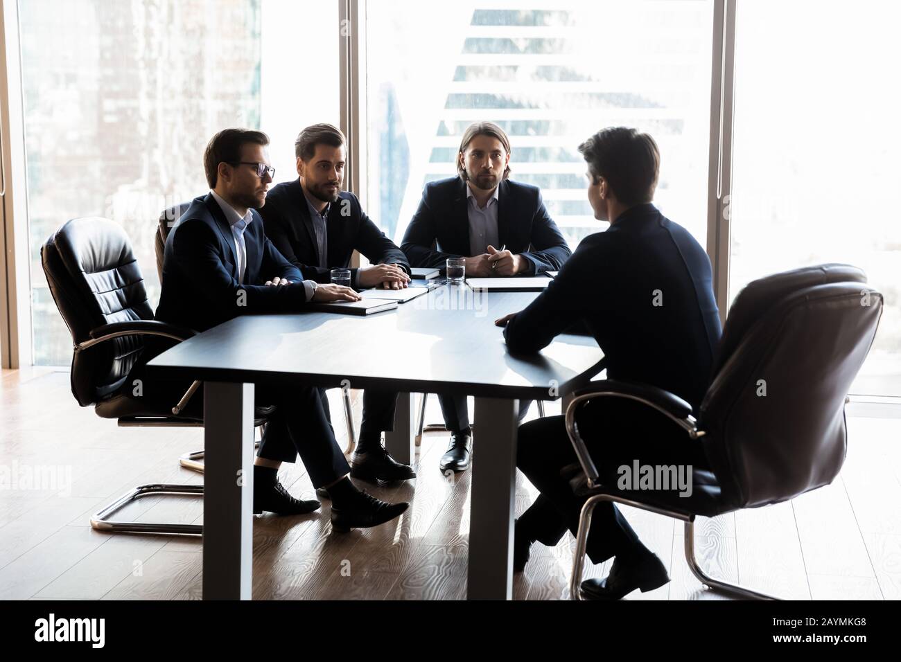 Applicant sitting in front three serious HR businessmen speaking. Stock Photo