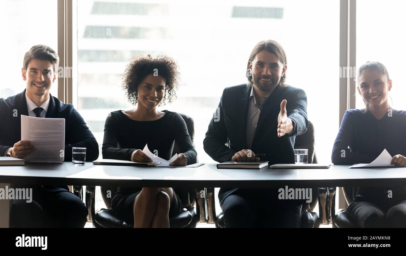 Happy diverse businessmen with applicant resume congratulating job seeker. Stock Photo