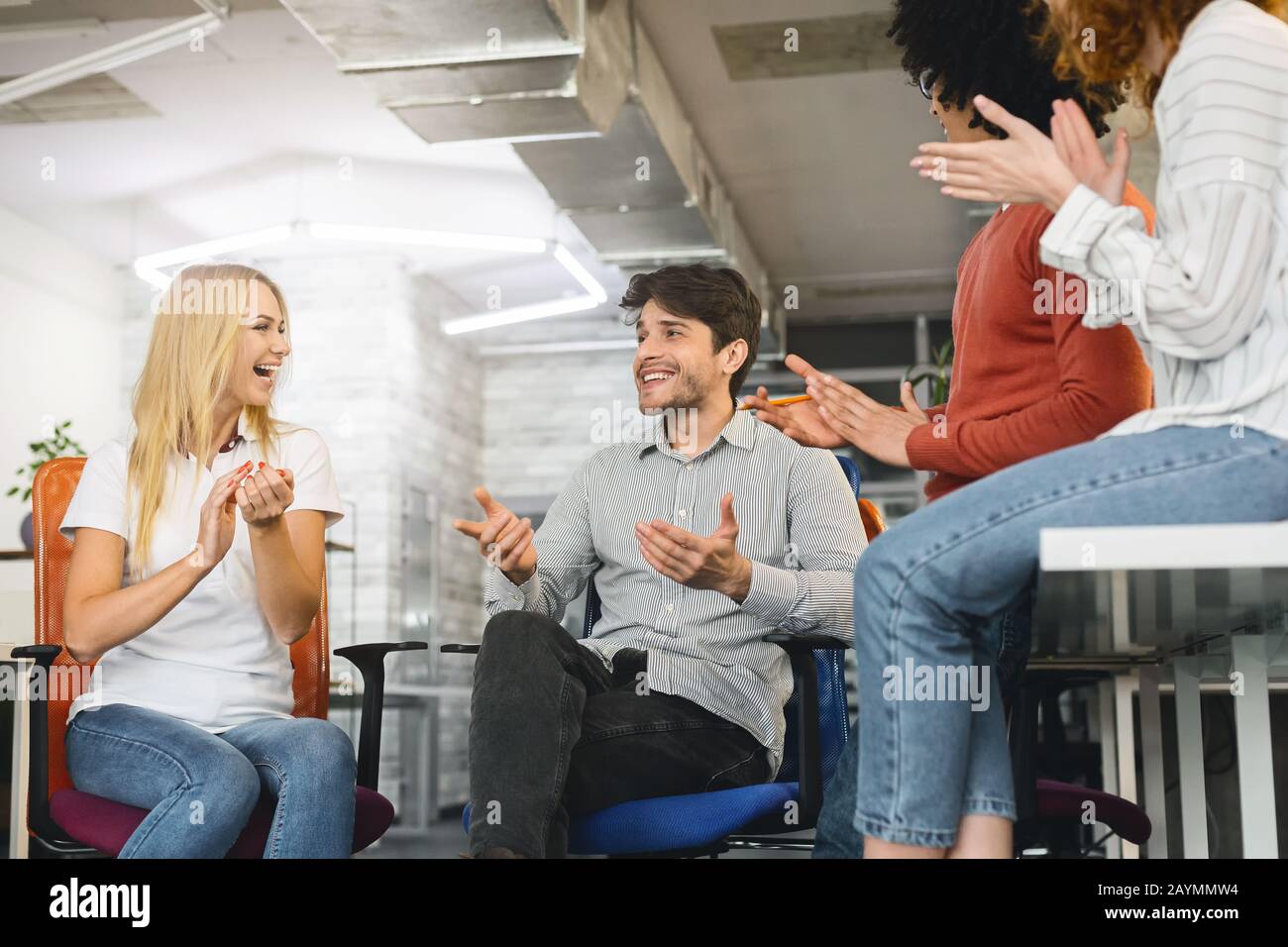 Positive group of colleagues having briefing, laughing and clapping Stock Photo