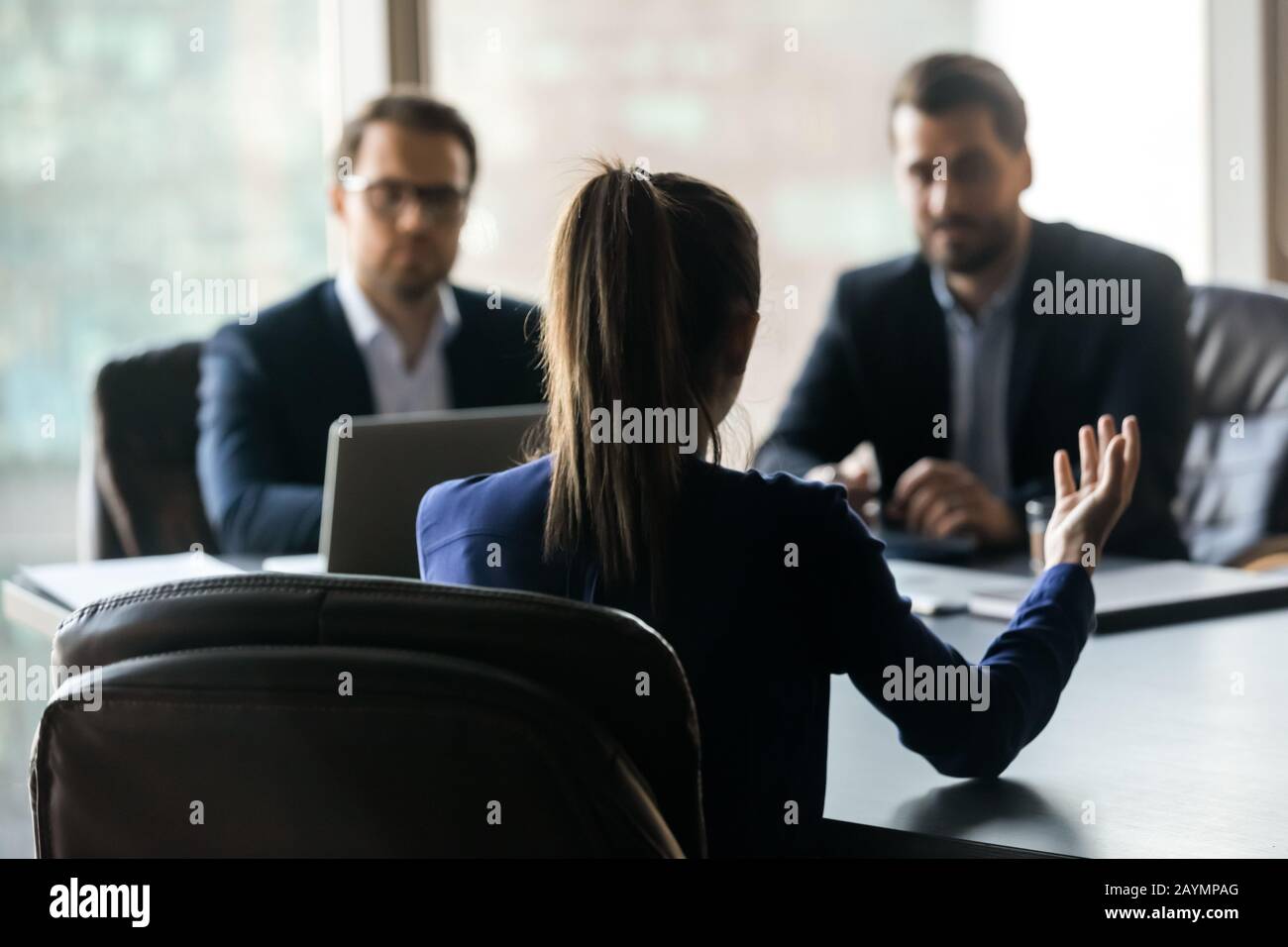 Hiring attractive woman applicant back sitting in front two HR. Stock Photo