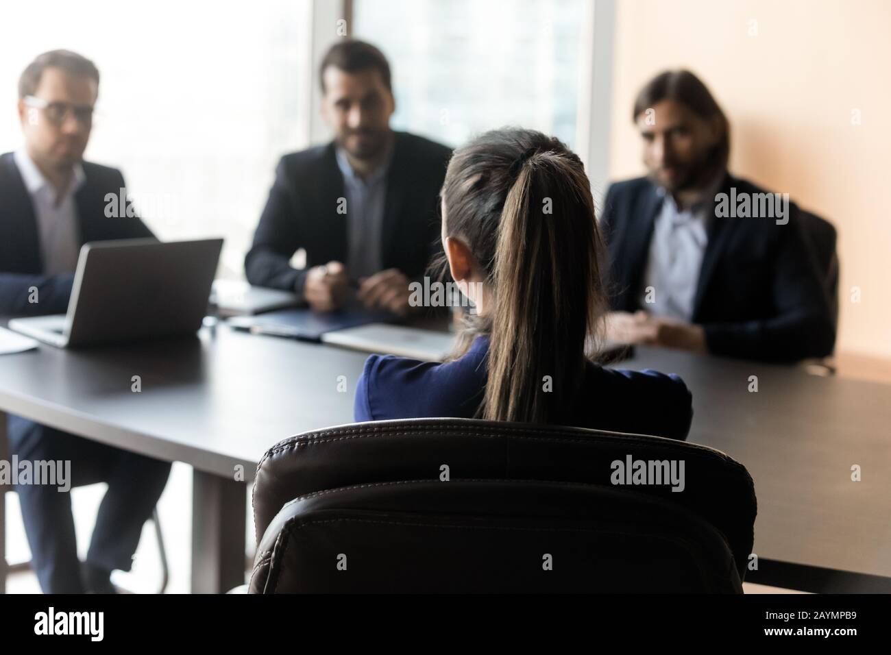 Attractive woman applicant back sitting in front HR businessmen speaking. Stock Photo
