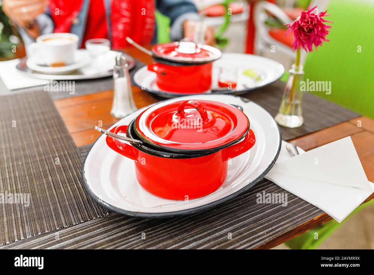 Tasty goulash soup in red pot casserole on a restaurant table Stock Photo