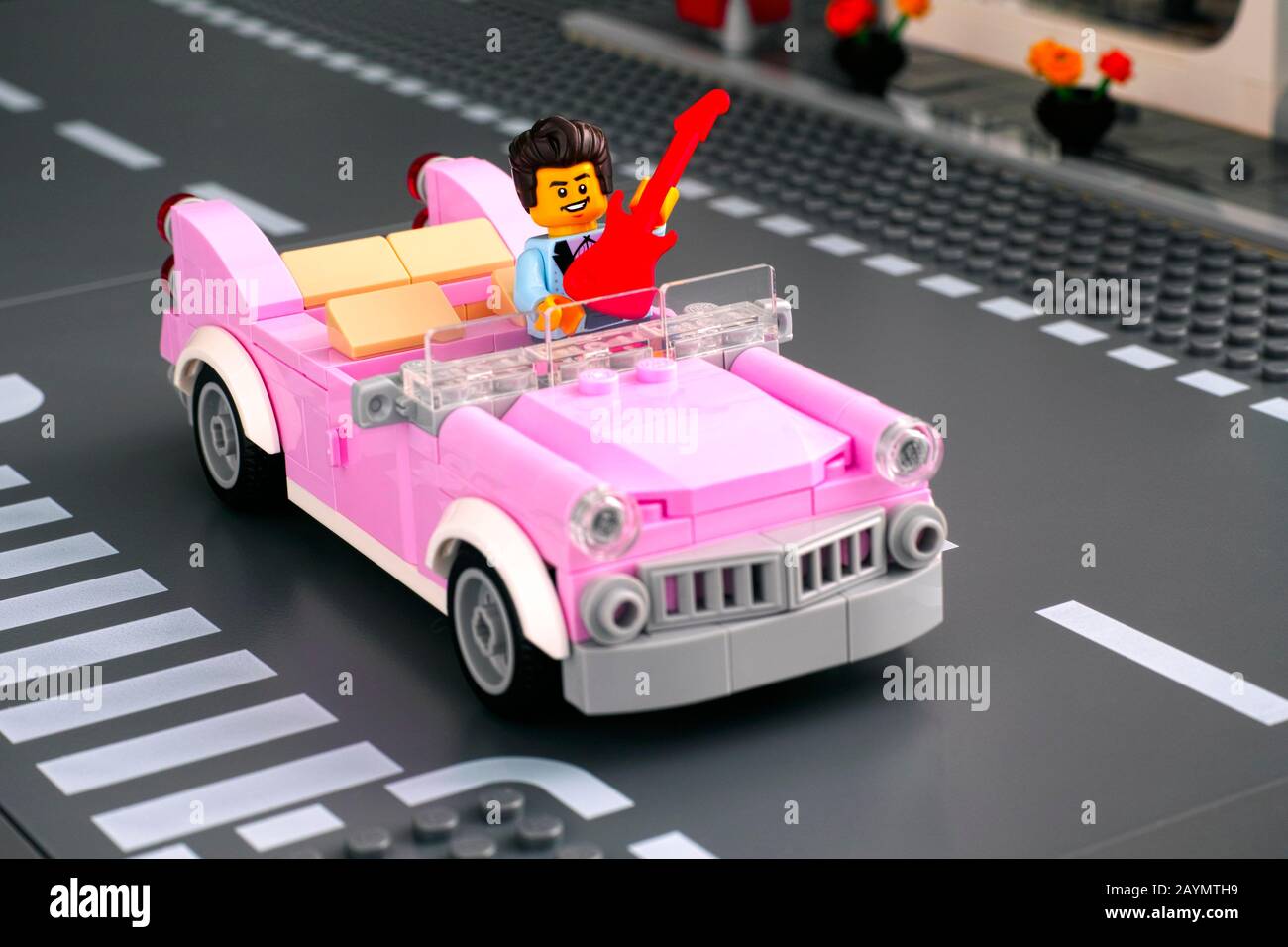 Tambov, Russian Federation - January 22, 2020 Lego rock n roll star minifigure with guitar in pink 1950s-style convertible on the road. Studio shot. Stock Photo