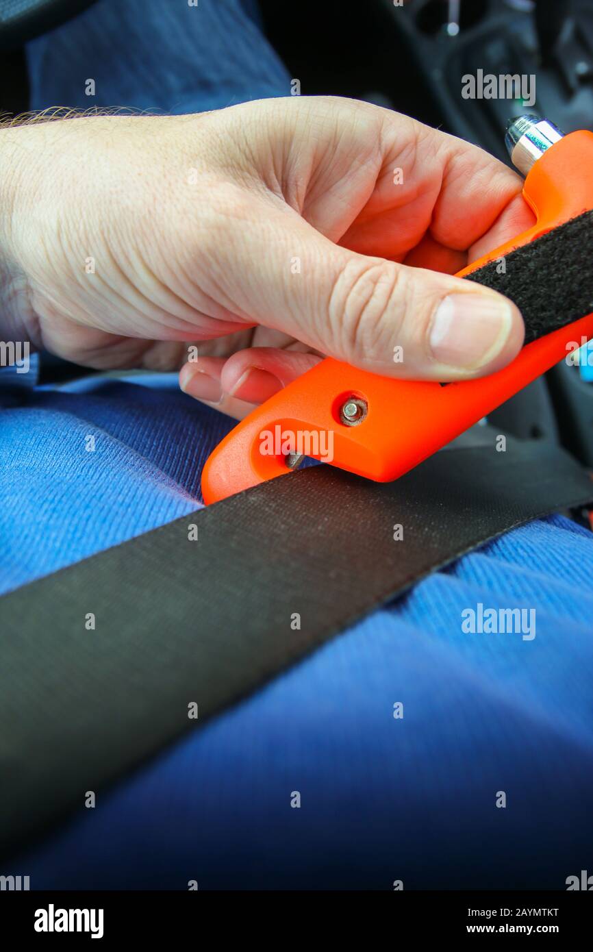 Safety hammer with seat belt cutter being used on seat belt during car