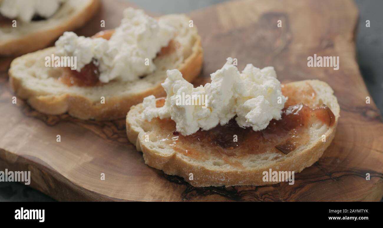 bruschetta with ricotta and fig marmalade on olive board, wide photo