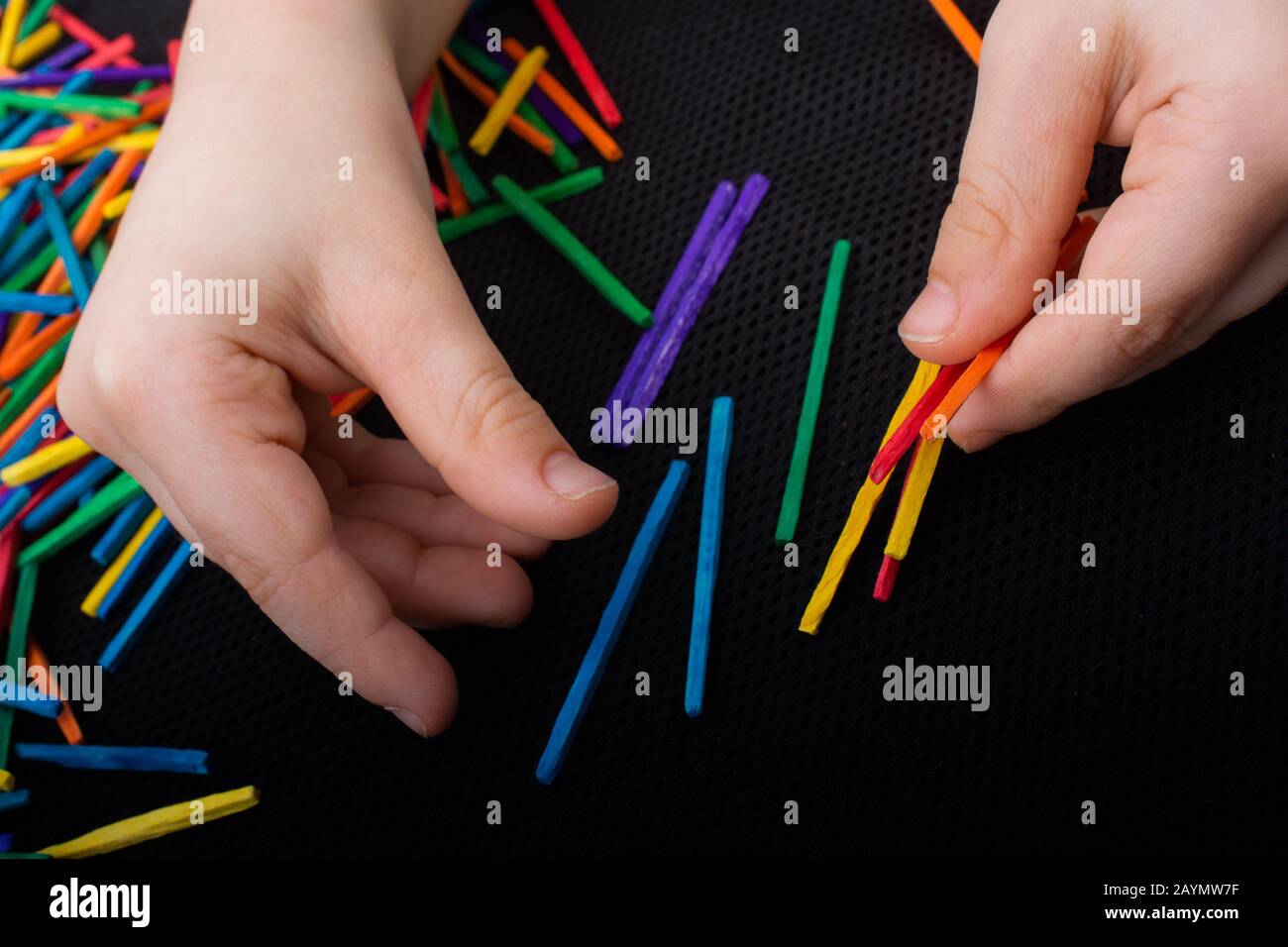 Kid playing with coloured wooden sticks for creativity on white ...