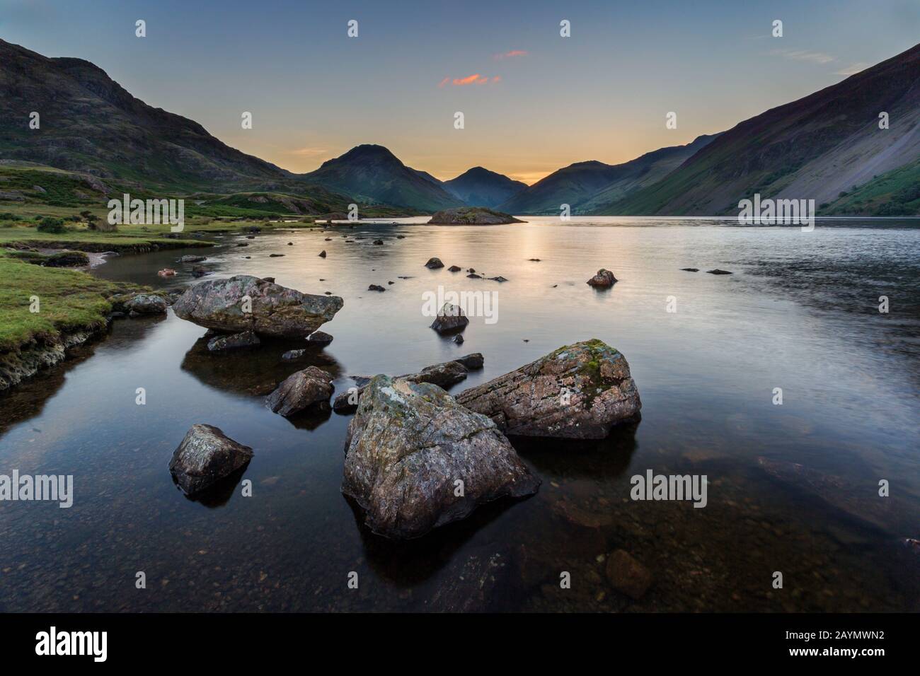 Sunrise at Wastwater looking towards Yewbarrow, Great Gable and Scafell, with rocks in the water, Lake District National Park, Cumbria, England, Uk Stock Photo
